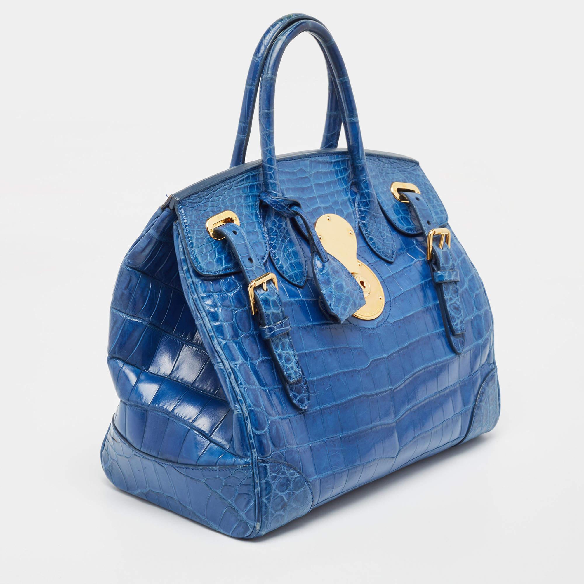 Classy in shape and design, this Ricky 33 tote by Ralph Lauren will be a loved addition to your closet. It has been crafted from crocodile leather and styled minimally with gold-tone hardware. It comes with two top handles and a leather-lined