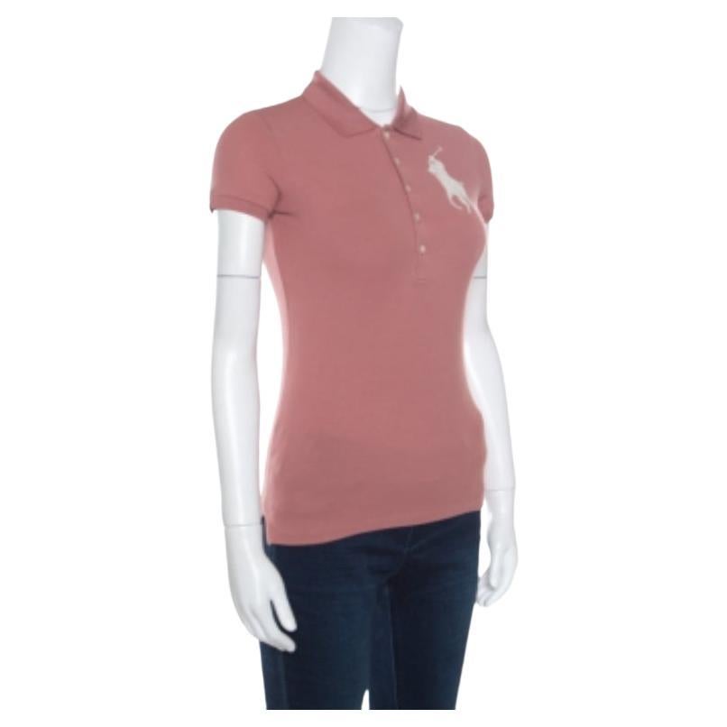 Dieses Polo-T-Shirt von Ralph Lauren ist so schick und fabelhaft! Die rosafarbene Kreation ist aus einer Baumwollmischung gefertigt und verfügt über einen klassischen Kragen, einen Knopfverschluss, kurze Ärmel und ein mit Perlen verziertes Logo auf