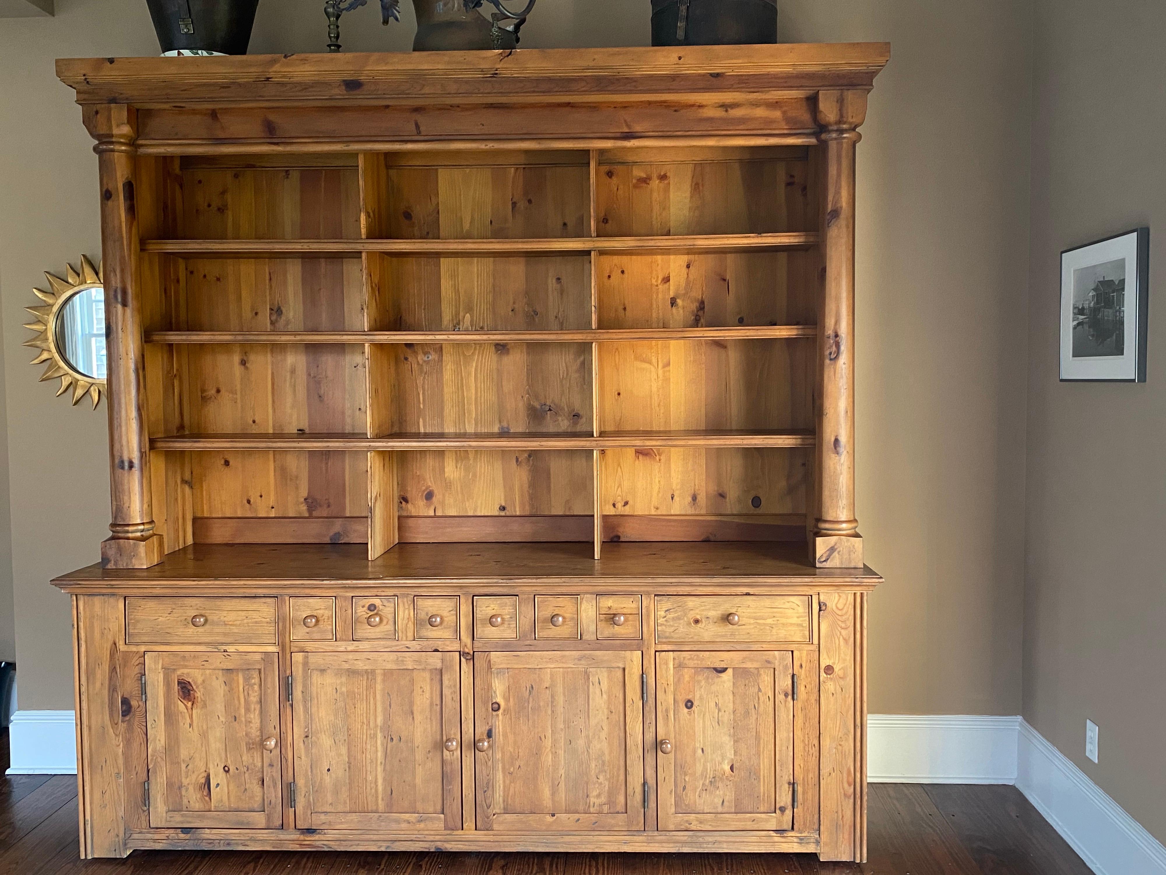 Ralph Lauren Bromley solid pine bookcase display hutch with storage base cabinet. Unit is two pieces that attach. The top features stepped cornice upheld by columns on either side. Three stationary shelves with three sections across. The bottom