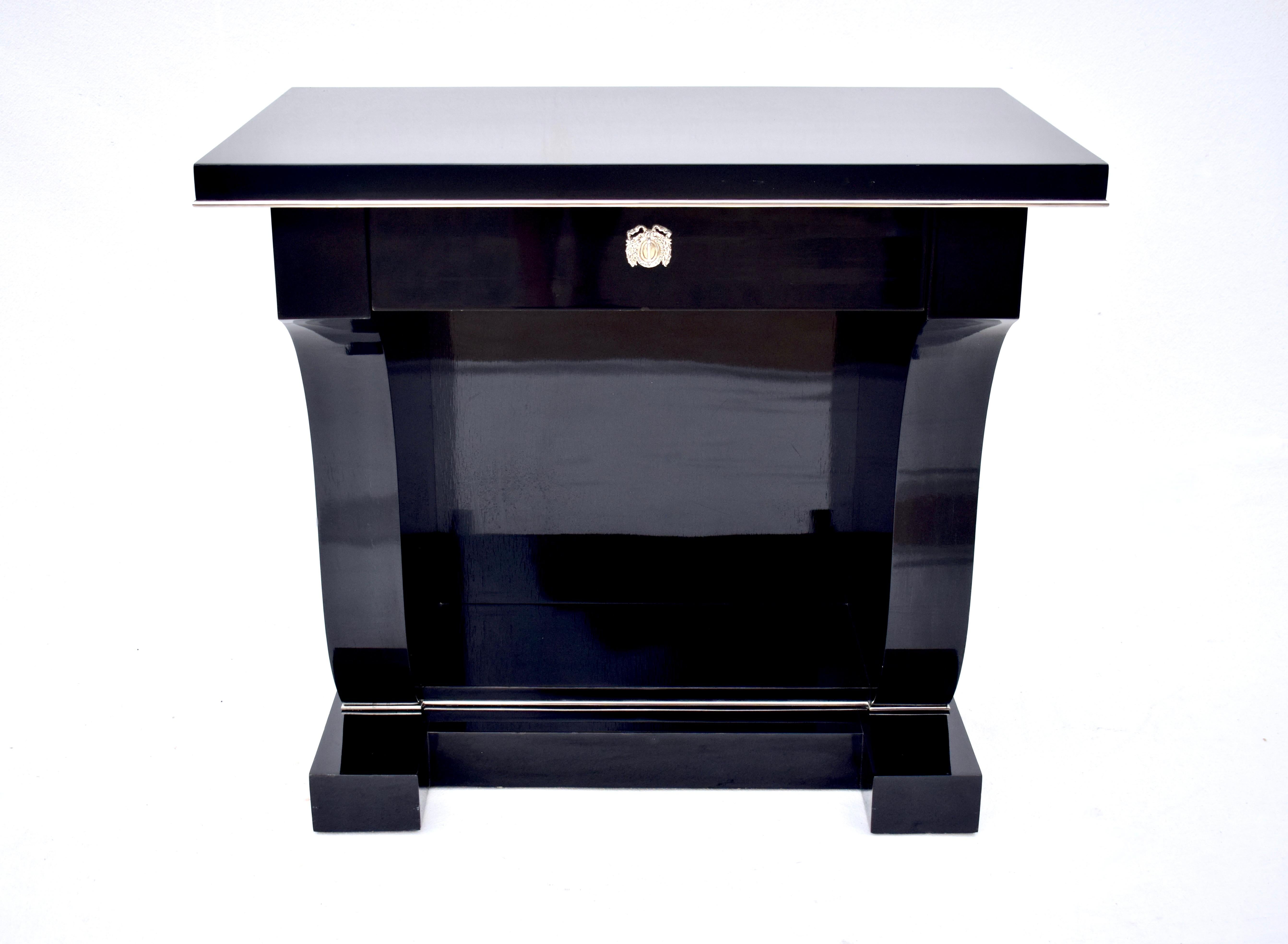 Ralph Lauren Home single drawer console with laurel wreath escutcheon & overhanging harp-shaped pedestal on a plinth base. A solid Mahogany piece boasting classical Empire Revival style with a modern flare in the high gloss black lacquer finish