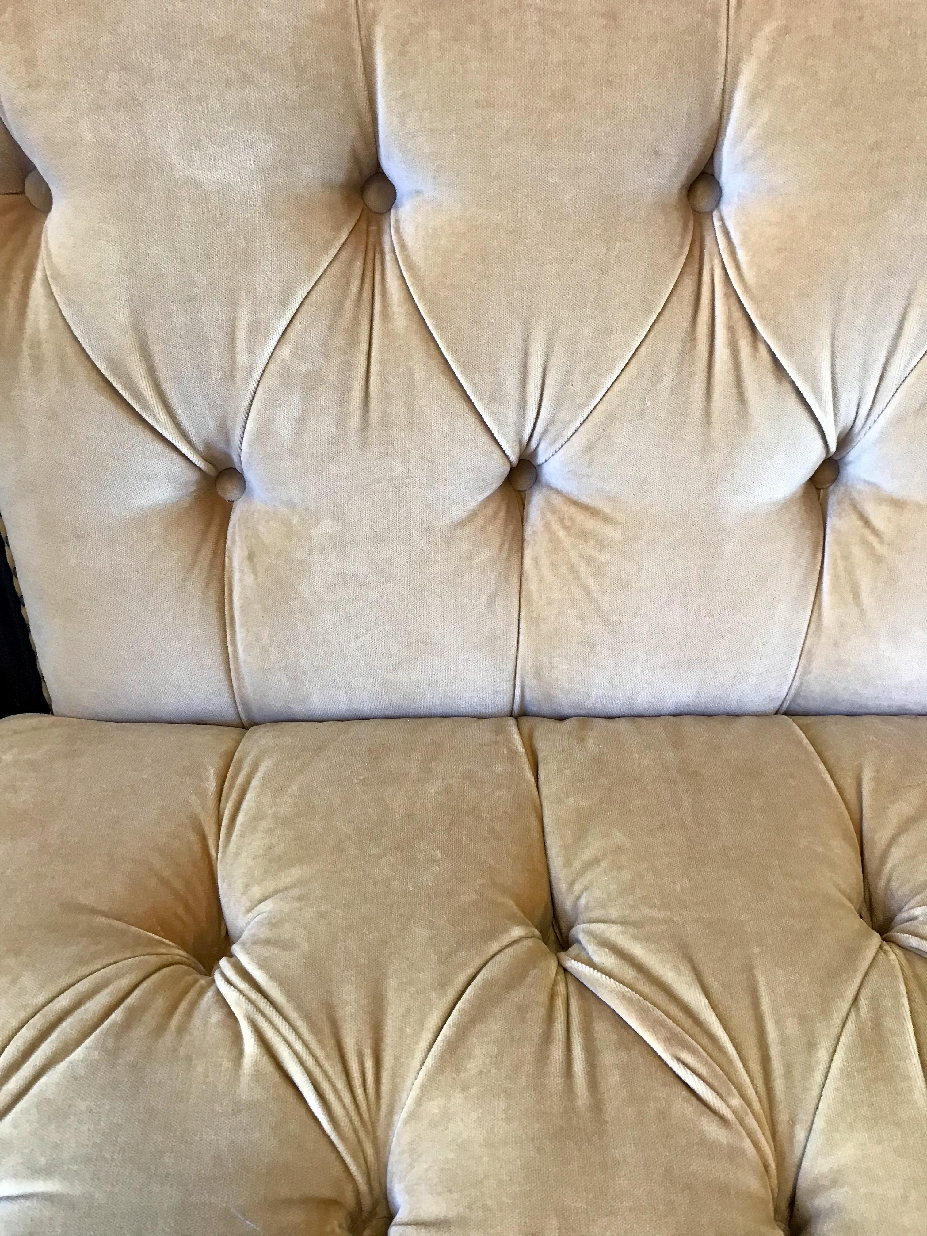 Done in subtle golden velvet fabric, the brass nailheads and caster, and a mahogany border, this Ralph Lauren chesterfield settee loveseat is nothing short of stunning.