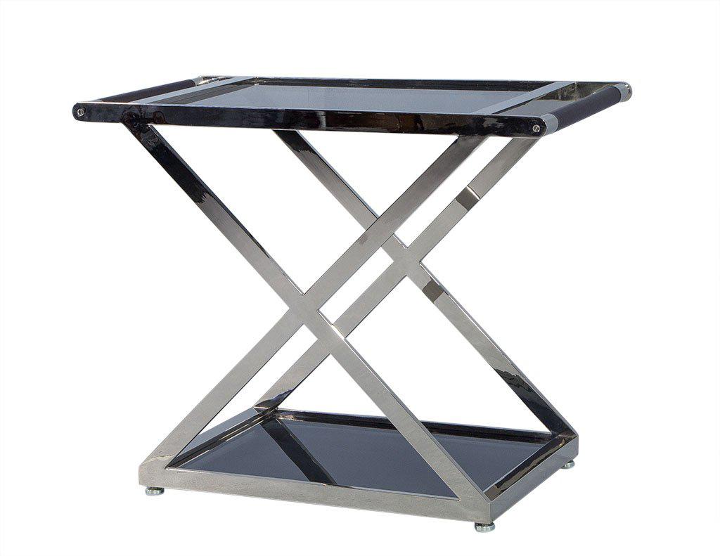 Ralph Lauren Cliff house bar. Featuring polished steel, cross-framed cart on steel casters with glass inset top and bottom shelf. Leather-wrapped handle with stitching details, design inspired from the 1930s.

Price includes complimentary curb