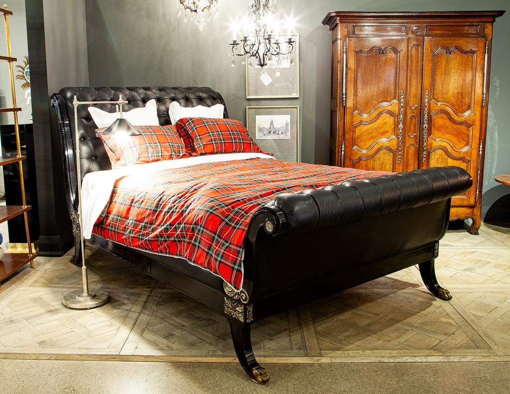 Ralph Lauren designed Clivedon Queen bed, Neo-Classical sleigh bed with scroll headboard and footboard upholstered in tufted supple black leather. Brass claw foot details and gilt accents add subtle embellishment. Completed in a high gloss black