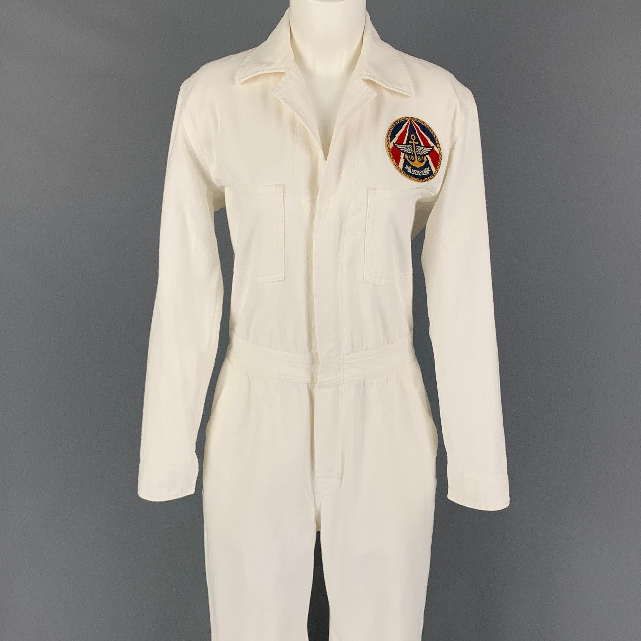 RALPH LAUREN Collection jumpsuit comes in a cream cotton featuring a camp collar, military patch, long sleeves, front pockets, and a zip up closure.
Very Good
Pre-Owned Condition. 

Marked:   8 

Measurements: 
 
Shoulder: 16 inches Bust:
38 inches