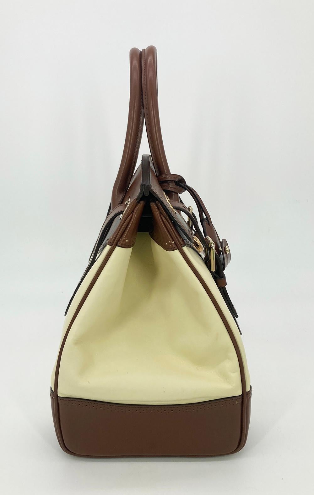 Ralph Lauren Cream and Brown Leather Rickey Bag in good condition. Cream leather body trimmed with brown leather and gold hardware. Signature rickey style with a front centered gold sliding latch lock and two buckles on either side. Double top