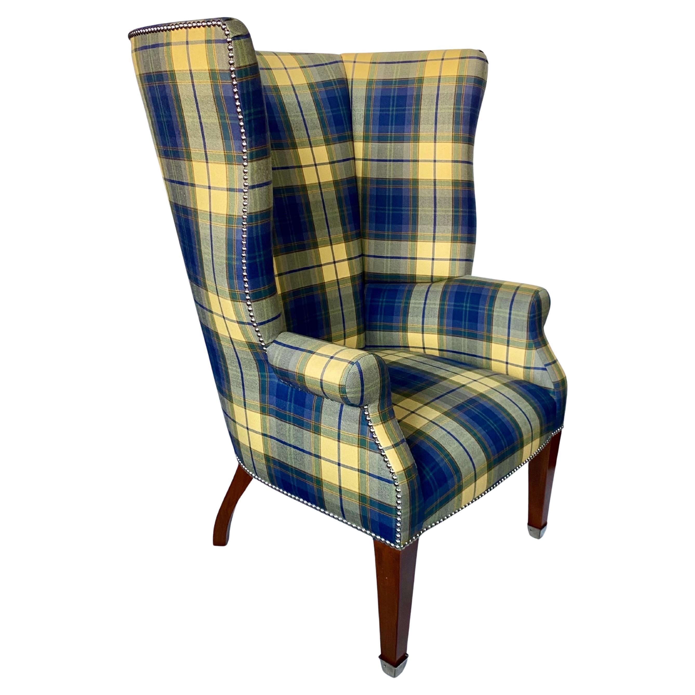 Handsome Ralph Lauren Hepplewhite high back wing chair upholstered in a classic blue and yellow wool plaid.  This tall sculptural lounge chair features a tight seat and back with polished nickel nail heads and front leg caps.  A timeless winged