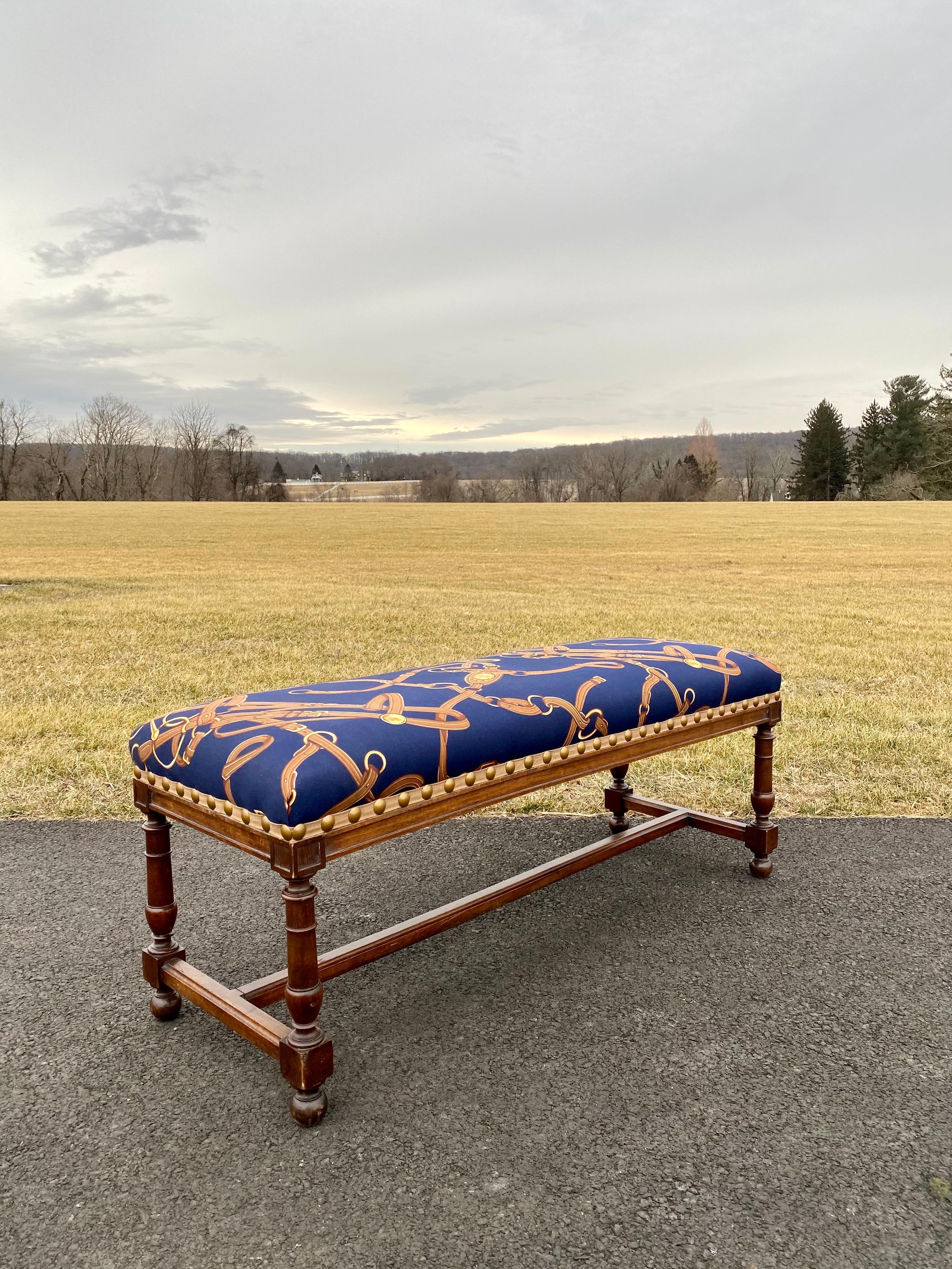 Classic vintage wood frame bench with wooden baluster turned legs and H-frame stretcher features professionally upholstered thick seating cushion with Ralph Lauren equestrian fabric with tangled horse bits and tacks. Cushion and fabric are soft and