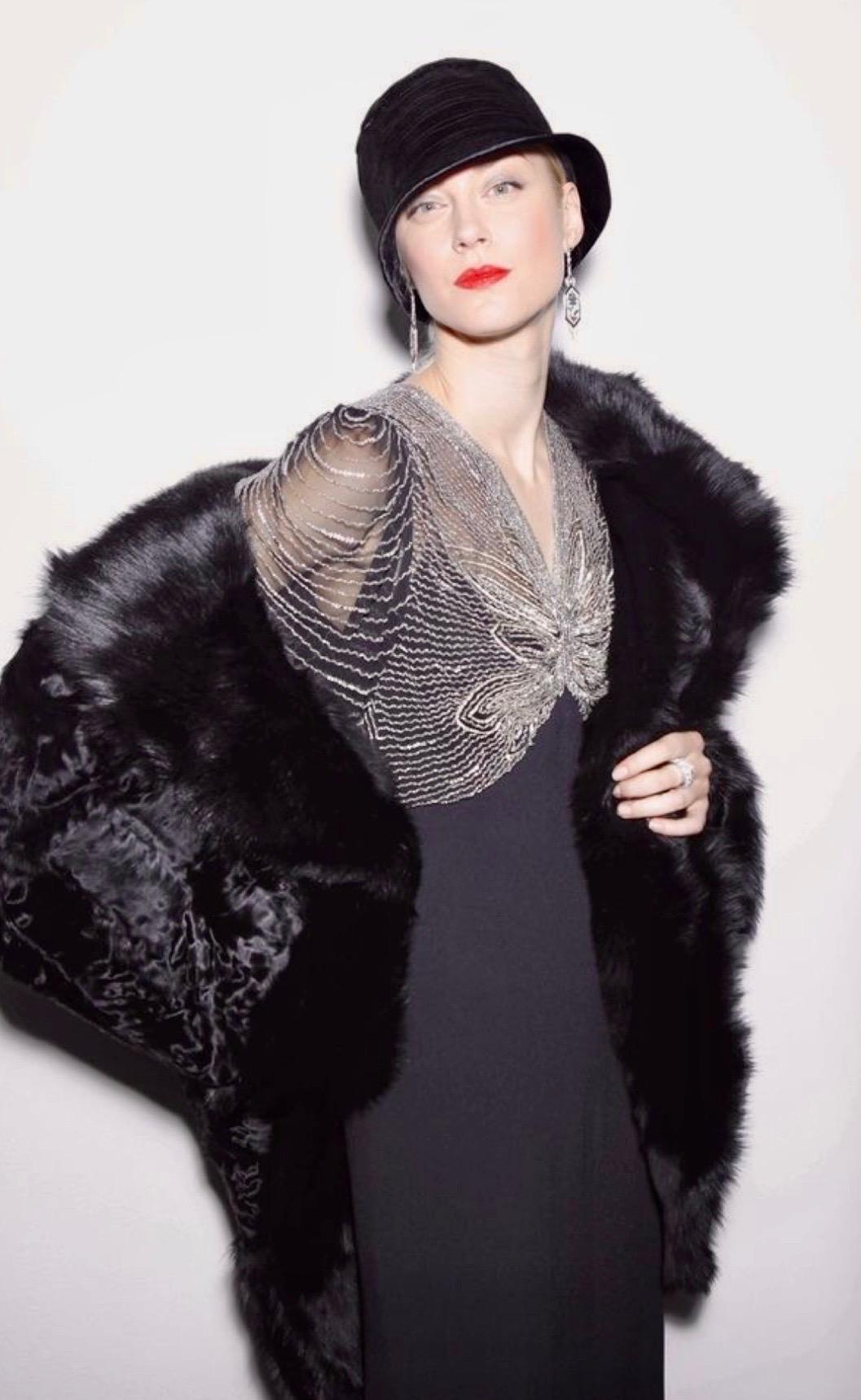 Striking Ralph Lauren runway evening gown from the Fall 2011 collection, shown on the catwalk with a fur coat and cloche hat for a dramatic, vintage-inspired look. Made in black crepe with a fluid, floor-length silhouette, the gown features a