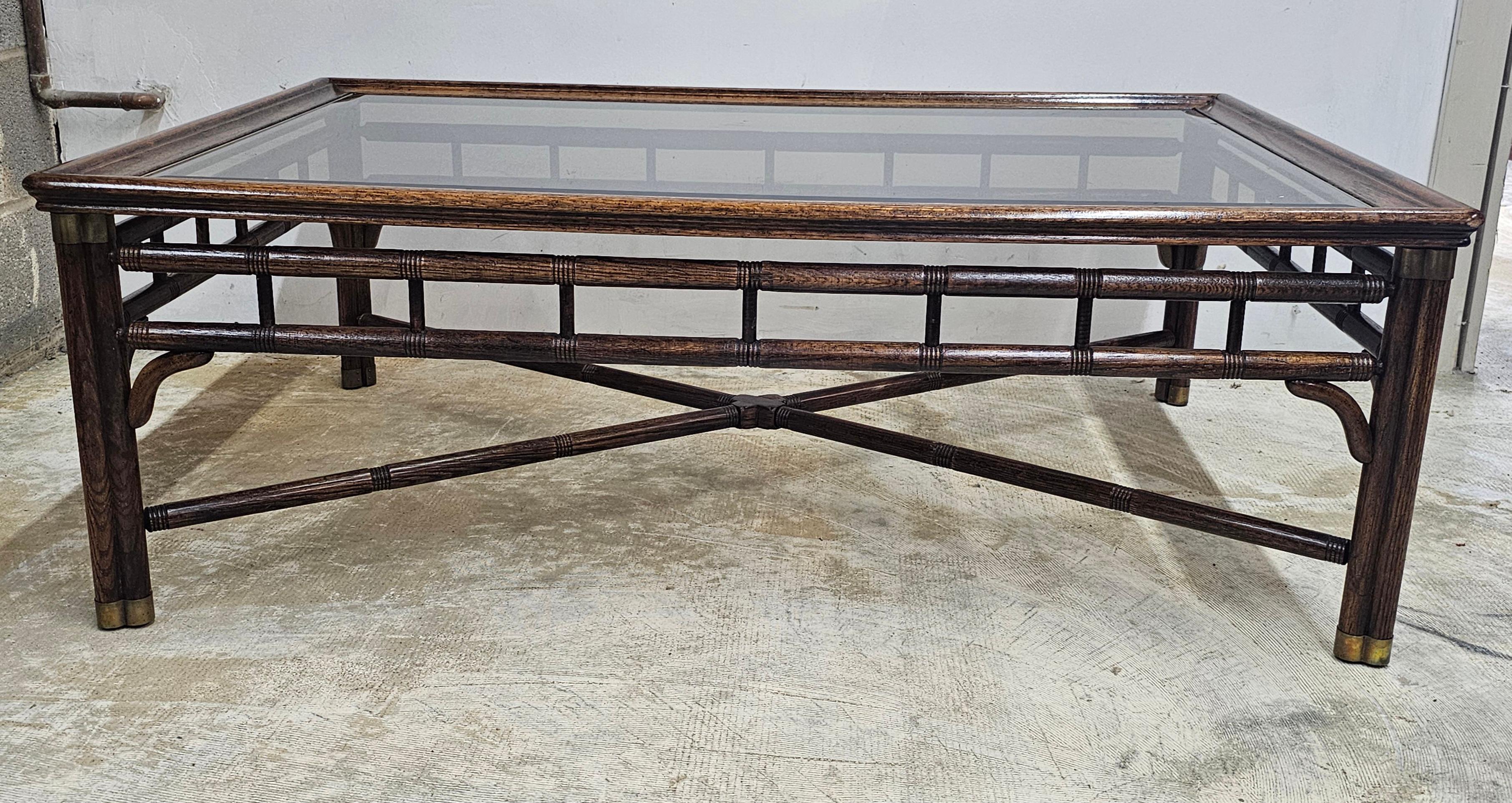 A Ralph Lauren Stacked Faux Bamboo Walnut and Glass Top inset with brass fittings coffee table.
Measures 48
