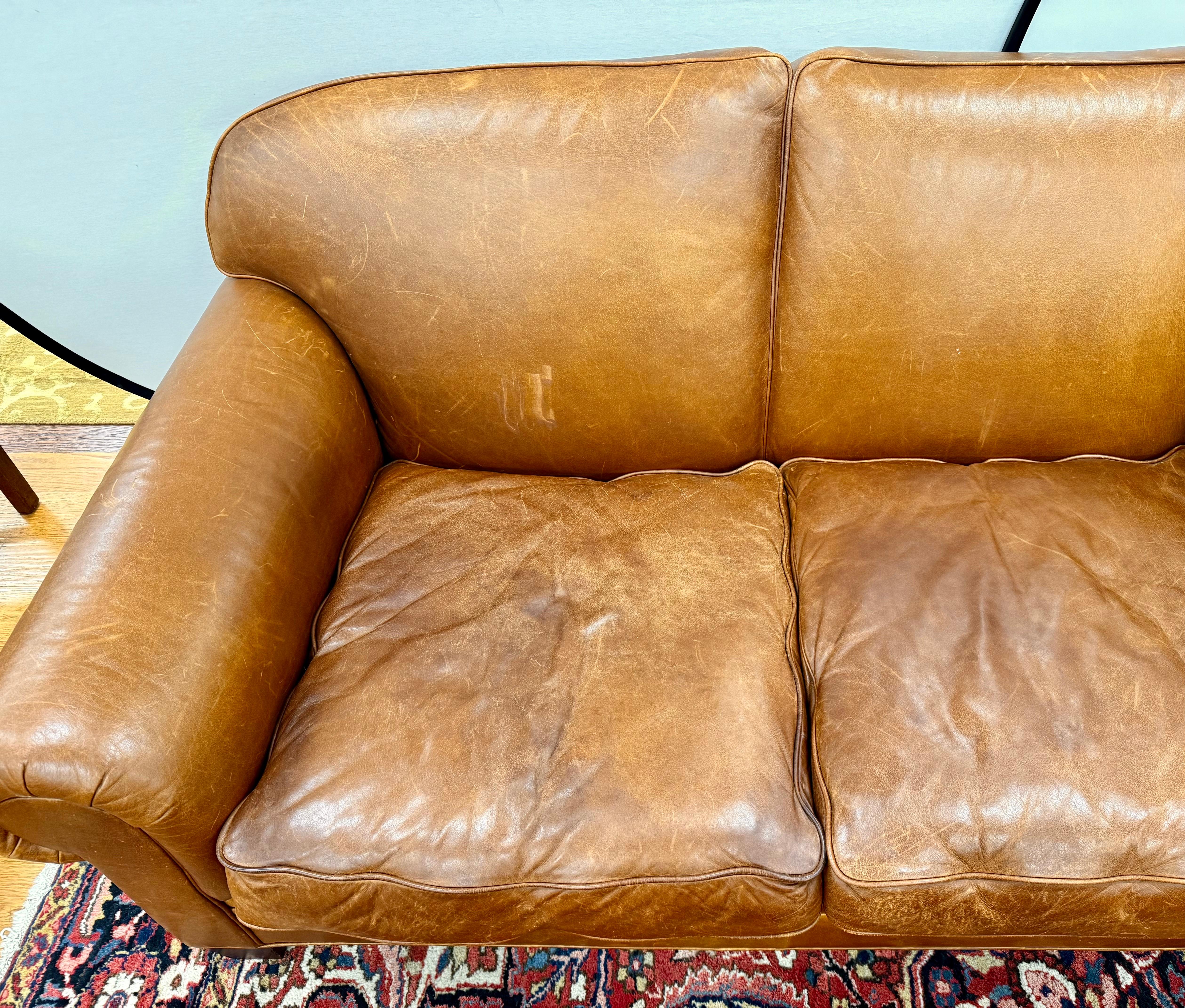 Expertly crafted with meticulous attention to detail, this generously sized three-seat sofa boasts supple top-grain leather in a rich caramel hue. This handsome high quality Ralph Lauren sofa features elegant rolled arms and a structured
