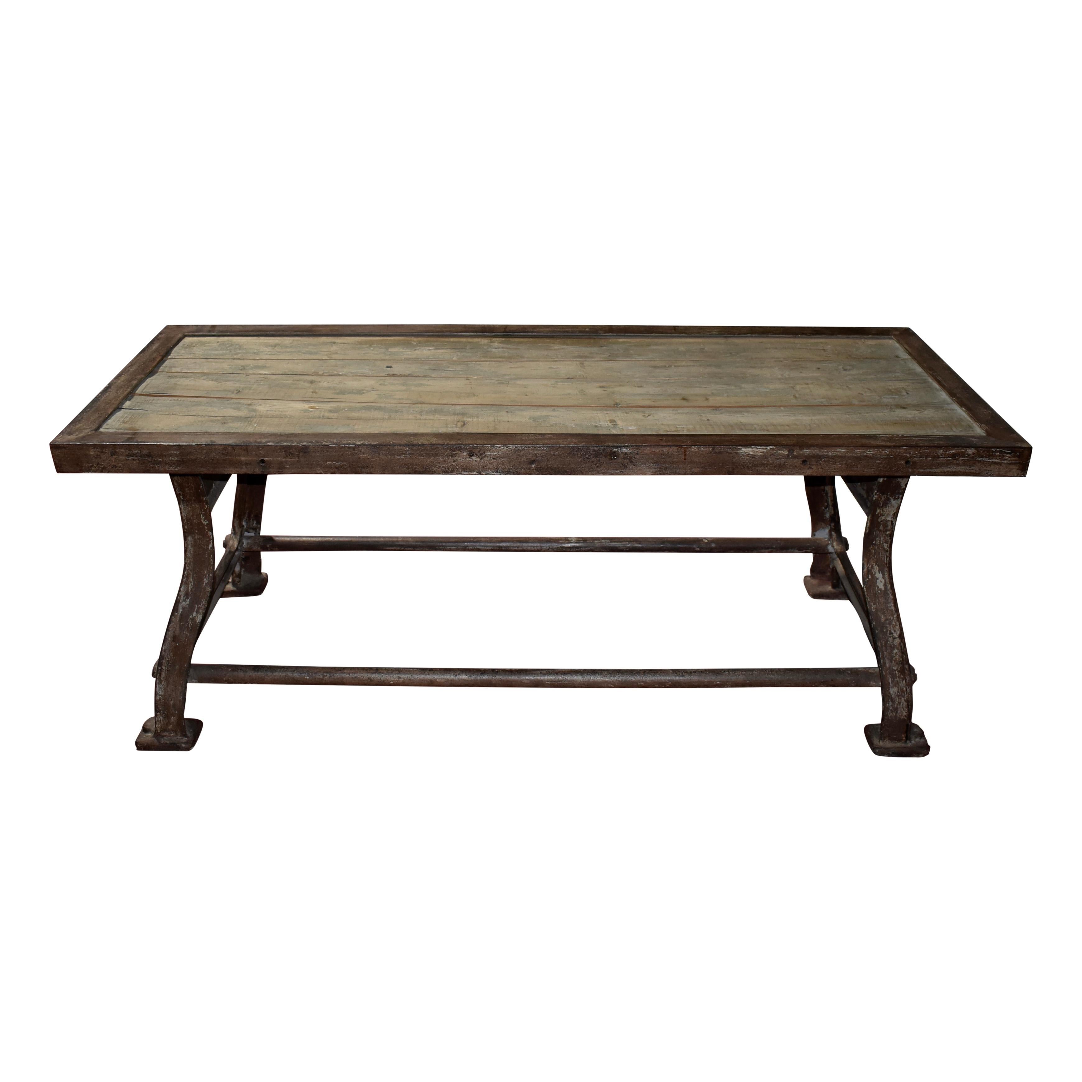 Sturdy and no nonsense, this industrial table features substantial iron legs united by iron stretchers. The wood plank top is framed in iron with intended separation between the planks, allowing the lower wood surface to show between the planks. The