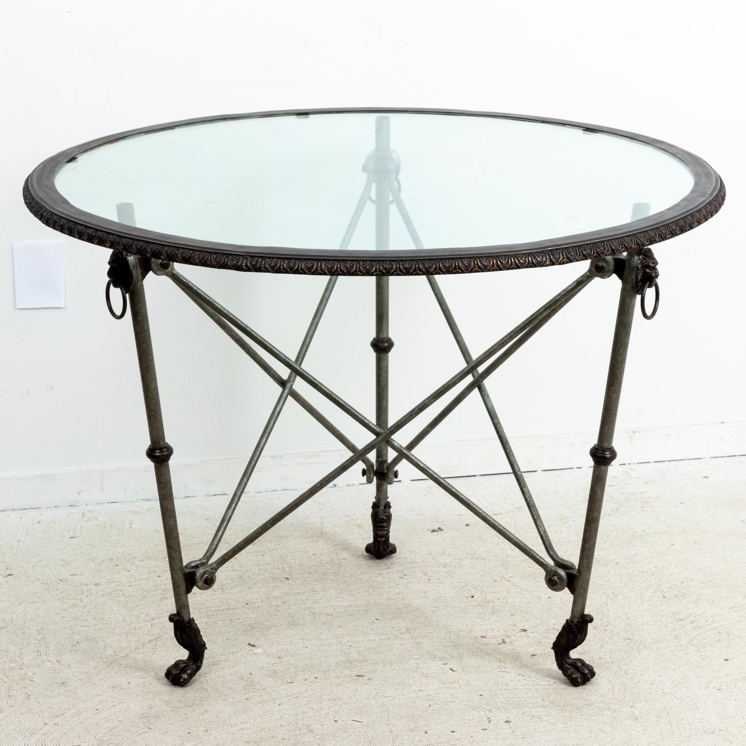 Circa 1980-1990s Ralph Lauren iron and glass gueridon lion's head table with bottom stretcher, lion's paw feet and removable tabletop. Made in the United States. Please note of wear consistent with age including some light scratches on the glass.