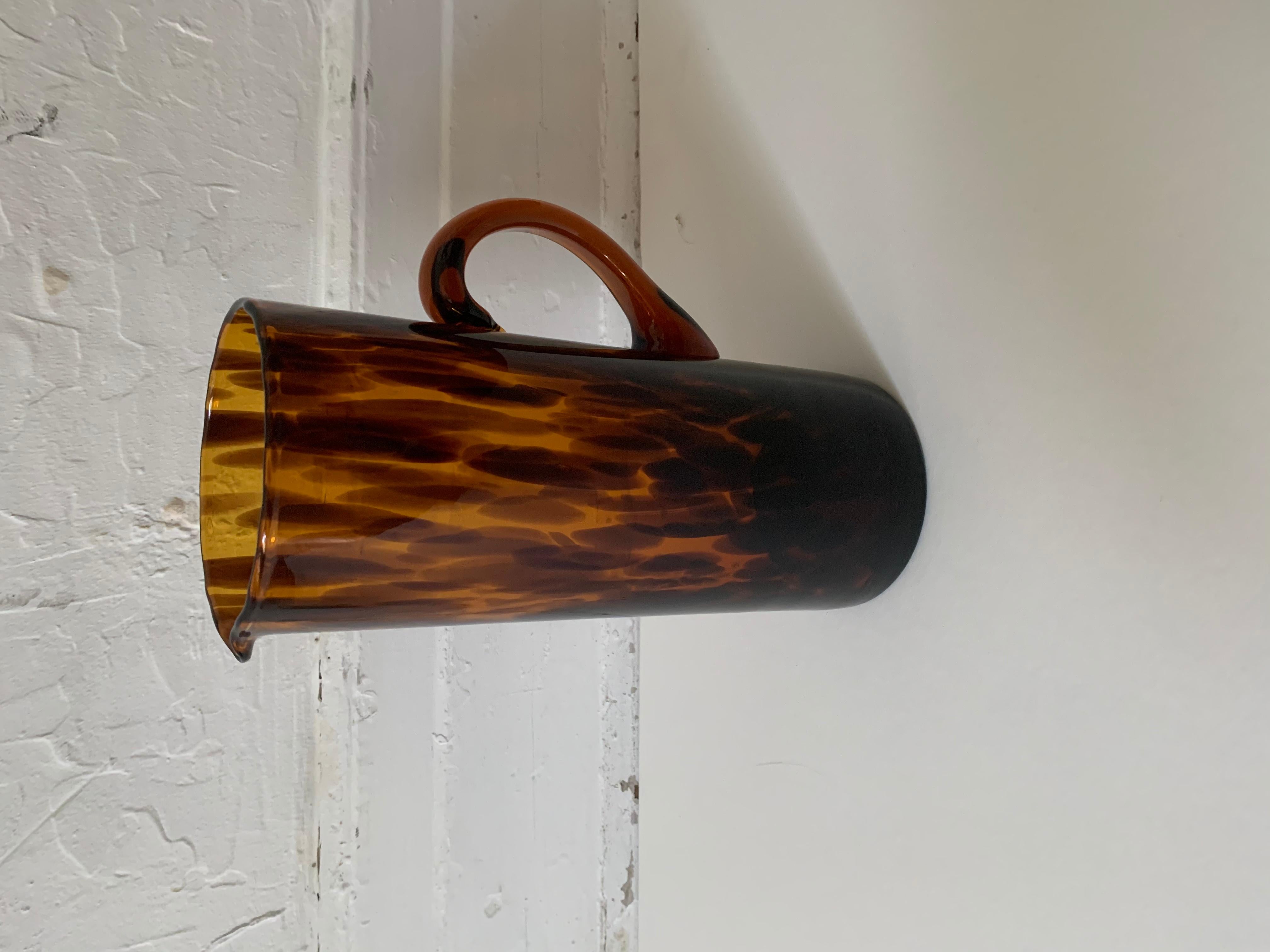 The Kendrick brown glass handled pitcher in tortoiseshell pattern by Ralph Lauren Home. Made in Italy, circa 2010. Acid etched brand stamp on underside.

Dimensions: 10.75 inches H x 6 inches L x 4.5 inches D.