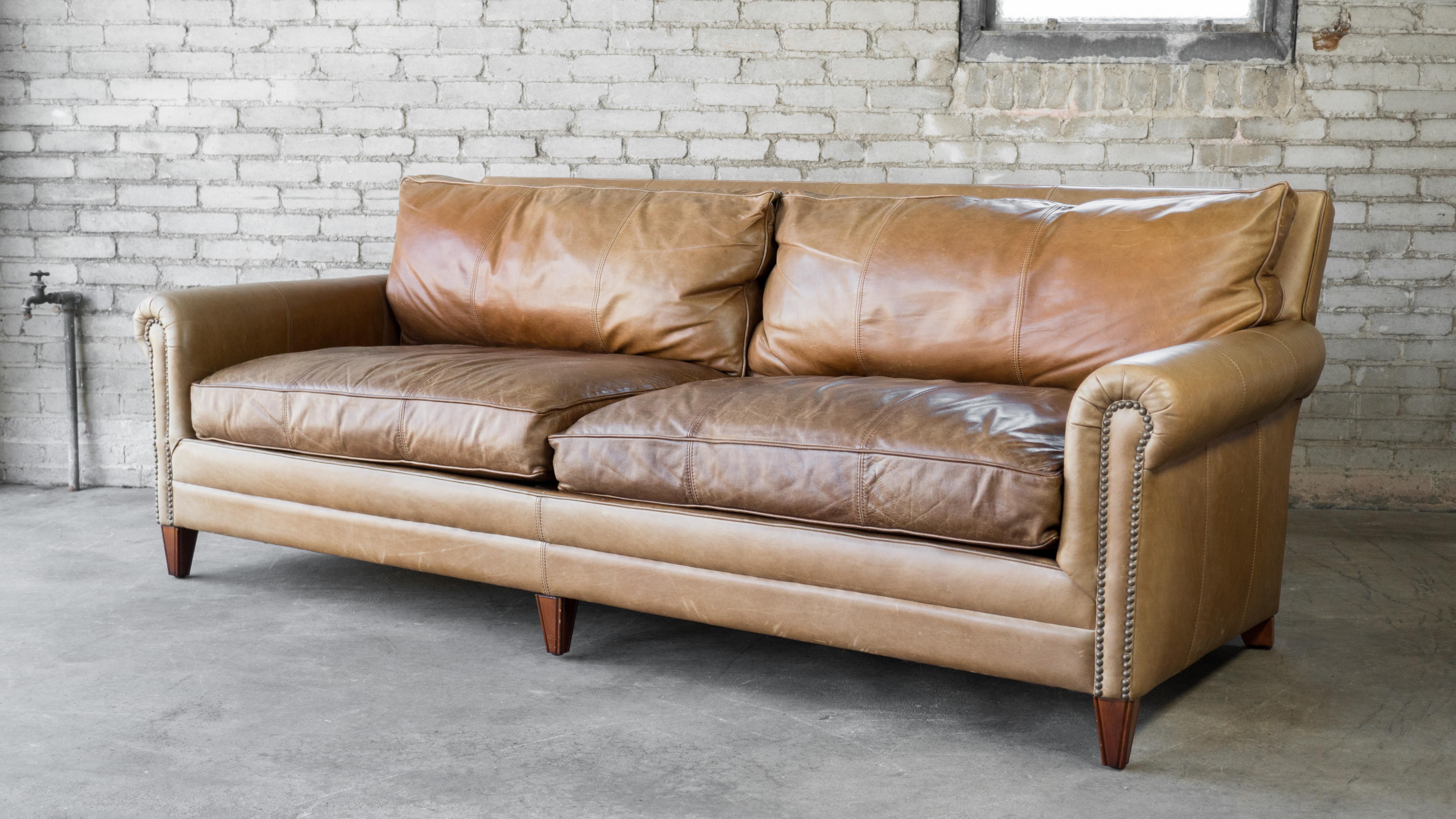 Gorgeous Ralph Lauren MacIntyre leather sofa. Wrapped in beautiful lightly distressed cigar brown leather with thick stitching details. Traditional English roll-arm style with paramount elegance and comfort. Brass nailhead trim. Oversized