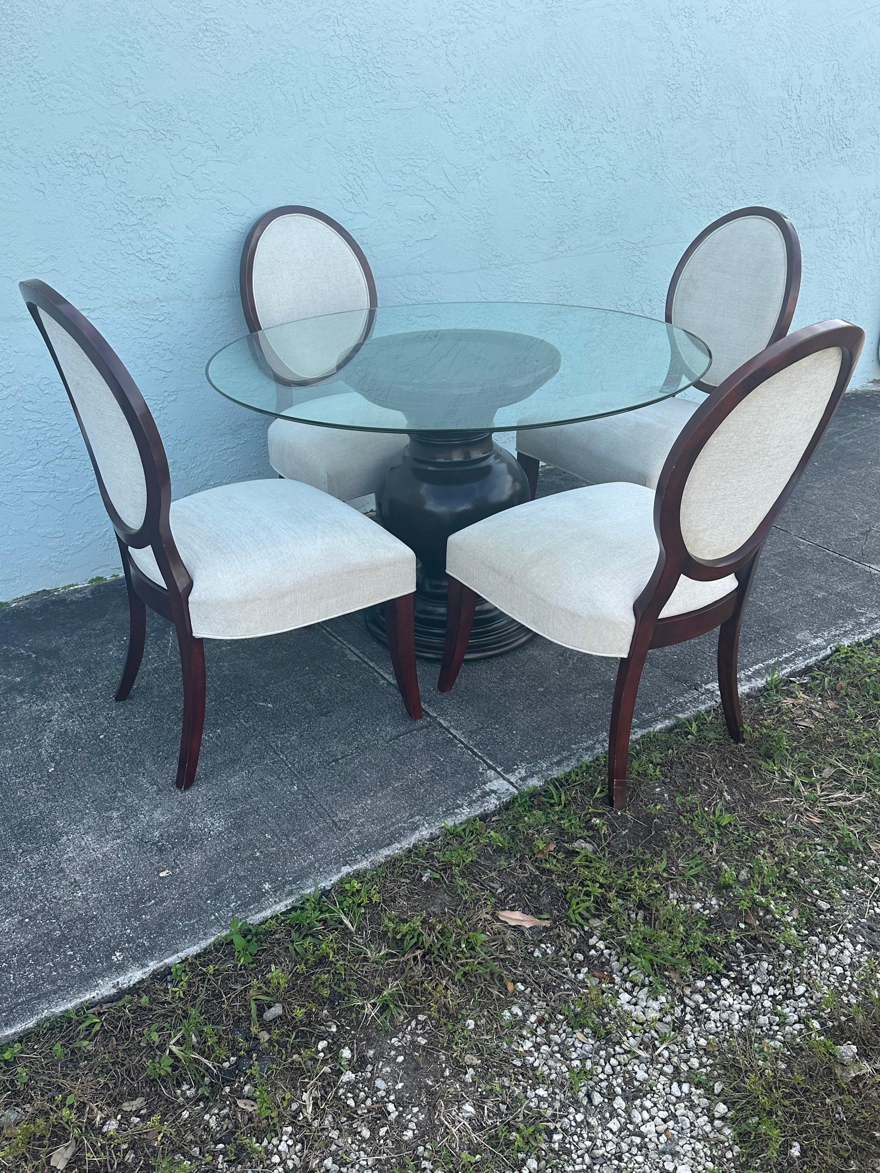 Fabriqué en acajou, ce guéridon sculpté comprend quatre chaises de salle à manger pour un ajout complet et luxueux à la salle à manger. Un plateau de table circulaire en verre et les chaises de salle à manger qui l'accompagnent sont tapissés de lin