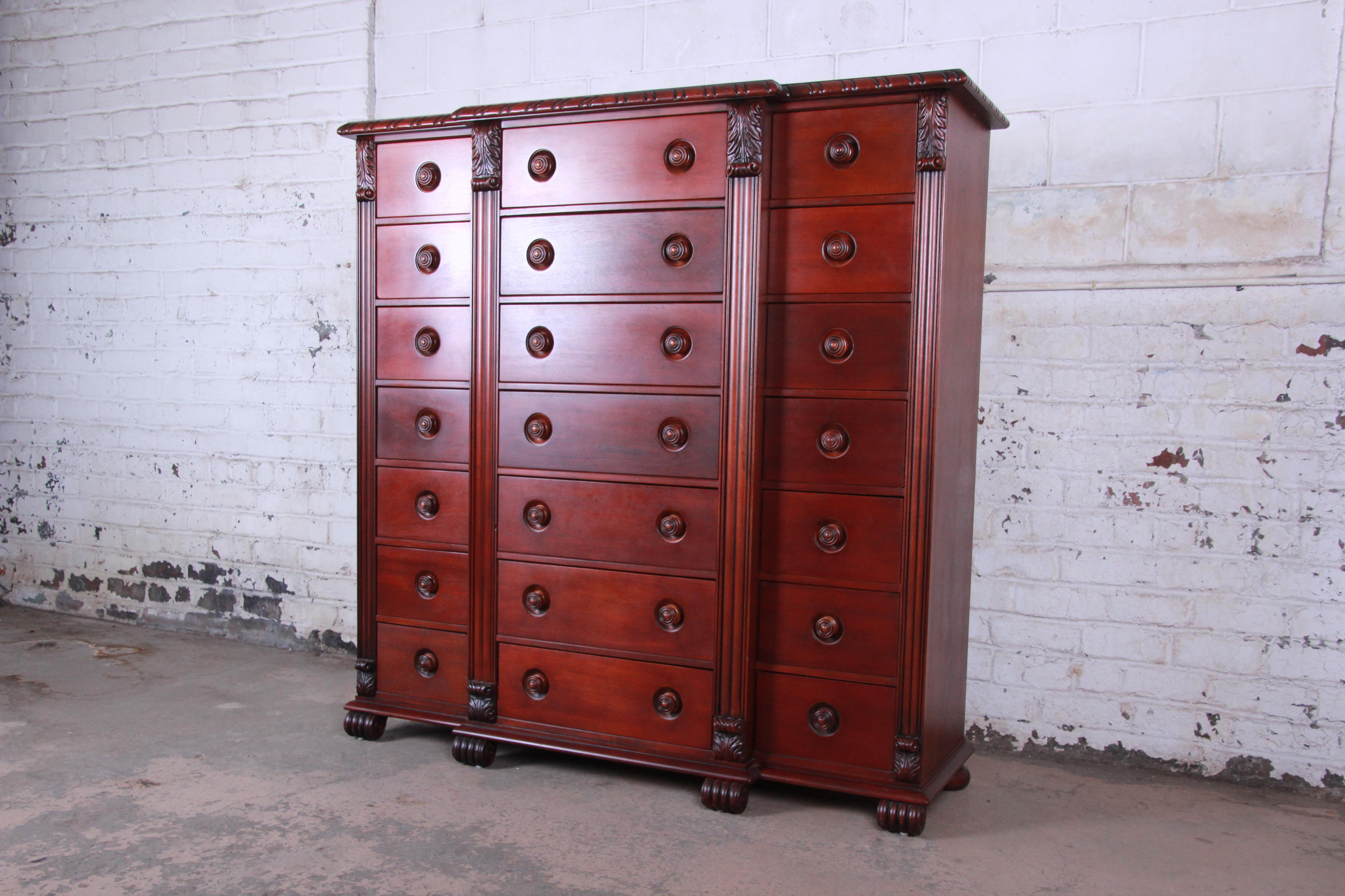 An exceptional 21-drawer neoclassical mahogany tall chest of drawers by Ralph Lauren. The dresser features stunning mahogany wood grain and beautiful carved wood details, with column style trim that frames all drawers with leaf accents to the top