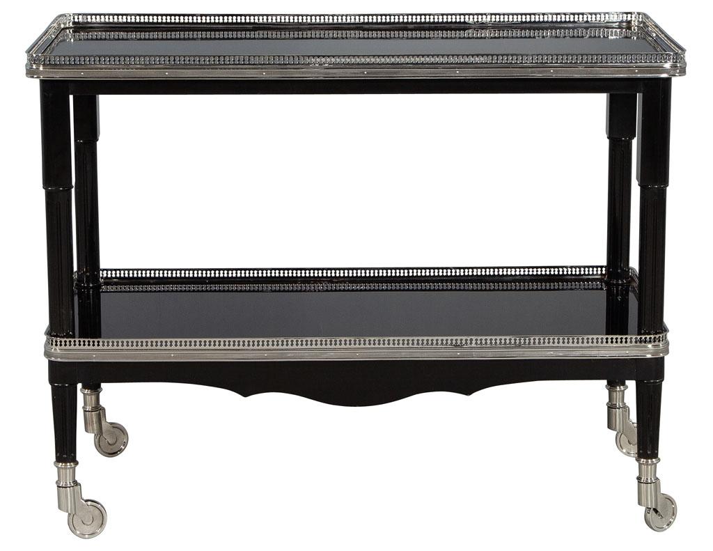 Ralph Lauren one fifth bar cart in black lacquer. This exquisite two tier Art Deco Inspired bar cart is made for entertaining! A hand polished top and bottom shelf is supported by four stainless steel castors and a polished stainless steel frieze on