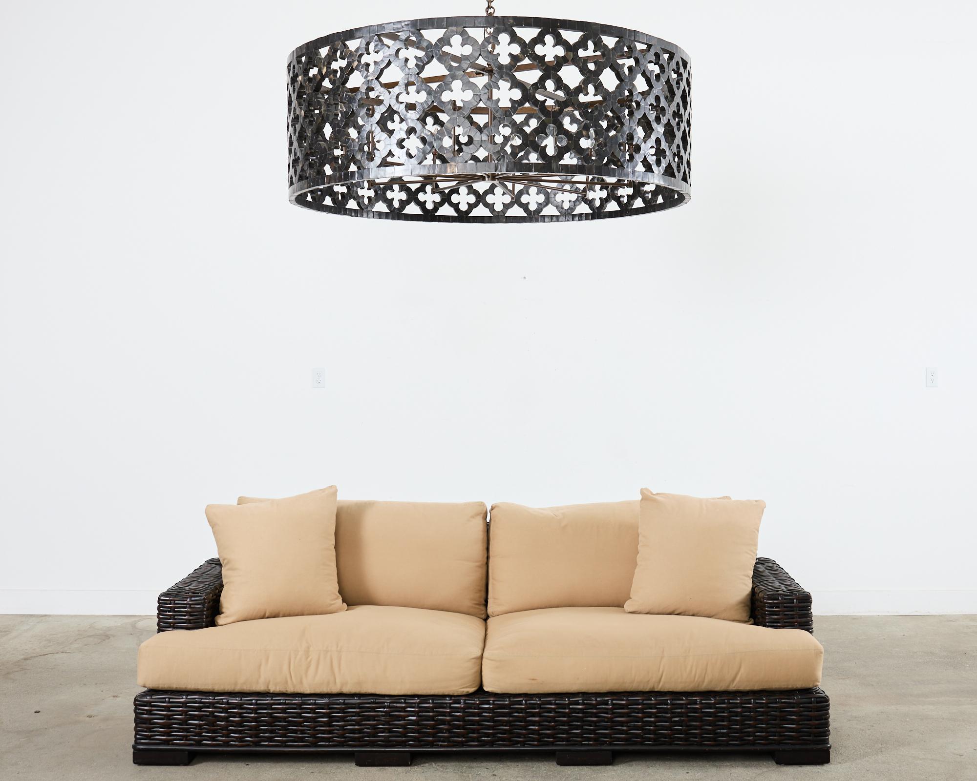 imposing sofa crafted from woven rattan in the organic modern coastal style by Ralph Lauren. The canyon sofa features an oversized hardwood frame completely covered with woven split reed rattan in a dramatic black mahogany finish. The frame is