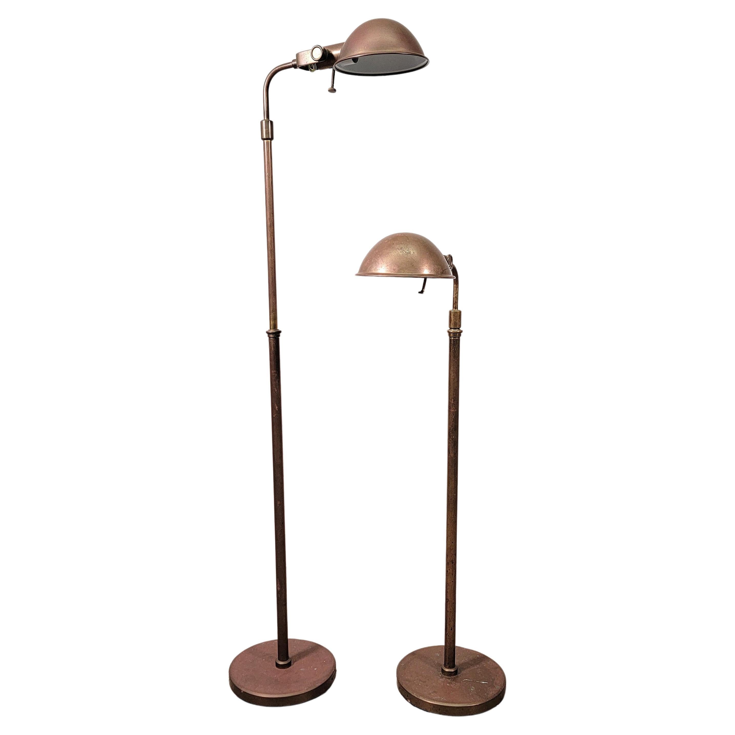 Pair of traditional brass pharmacy floor lamps by Ralph Lauren. The patinated brass lamps features adjustable height, arms and dome shades. The height ranges from approximately 41 in (around 104 cm) to 56 in (142.24 cm) total maximum height. Local