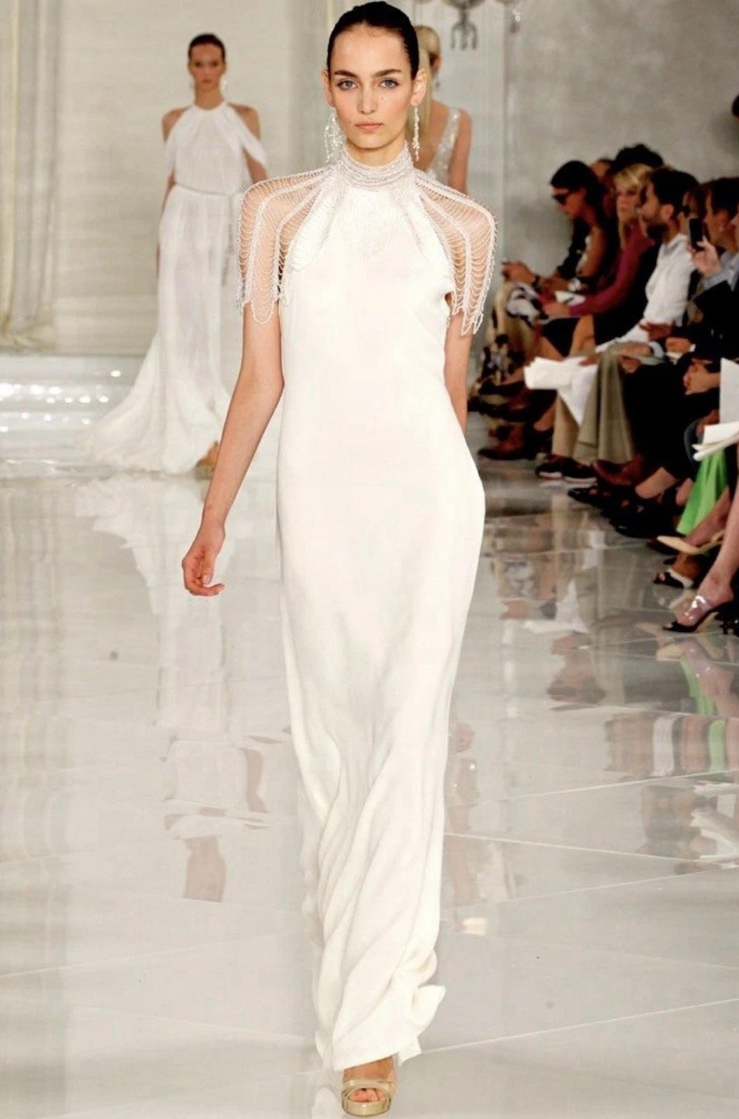 From Ralph Lauren's Iconic Spring 2012 Collection, this rare runway wedding gown is a breathtaking example of modern couture with timeless elegance. Crafted in fluid white viscose crepe, the gown features a sculptural high mock neck and dramatic
