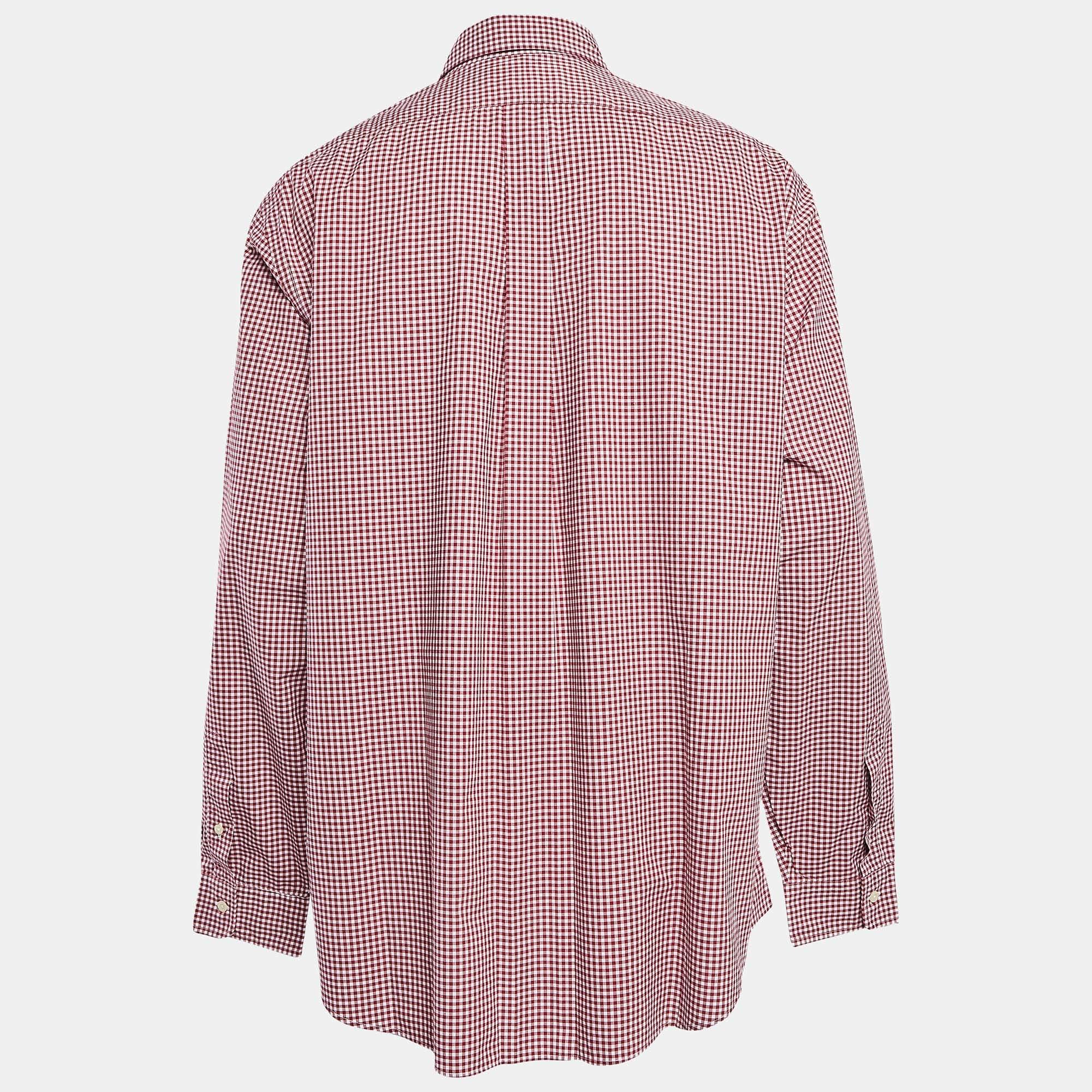 Una camicia Ralph Lauren confezionata in popeline e ricoperta di quadretti rossi Gingham. La camicia da uomo ha bottoni frontali, maniche lunghe e una vestibilità comoda.