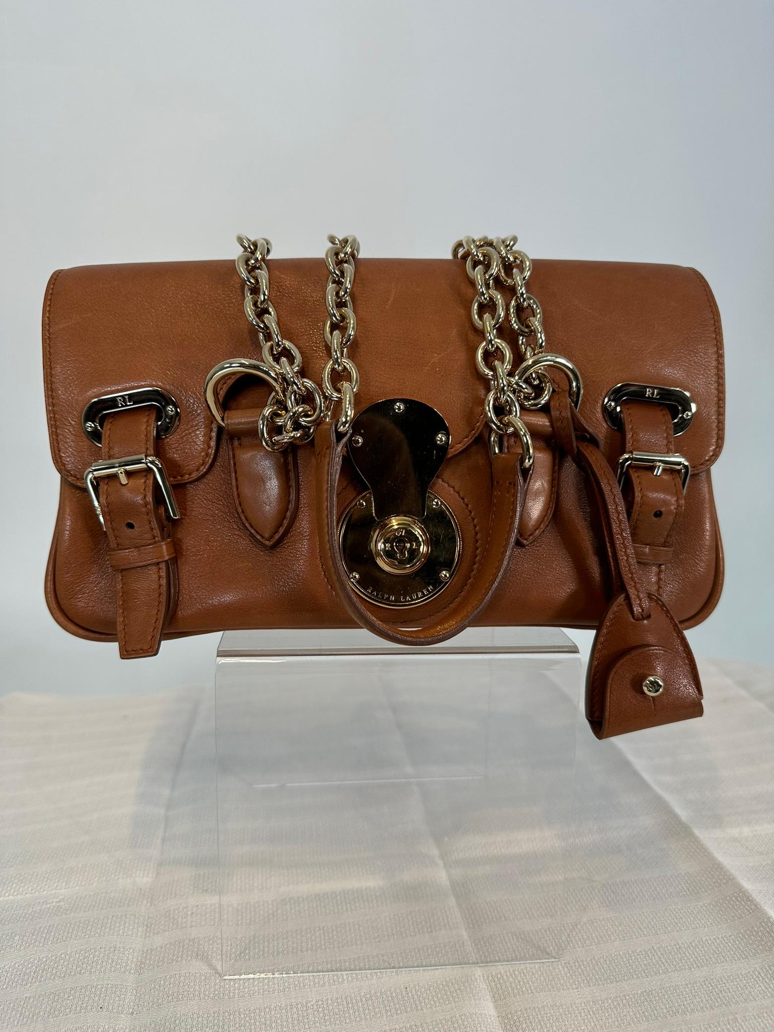 Ralph Lauren Ricky shoulder bag with gold chain handles & leather shoulder tops. Baguette style bag with double strap & buckle closures at the front, gold metal hardware and gold metal circle lock plate. Key cloche & 2 keys. The interior of the bag