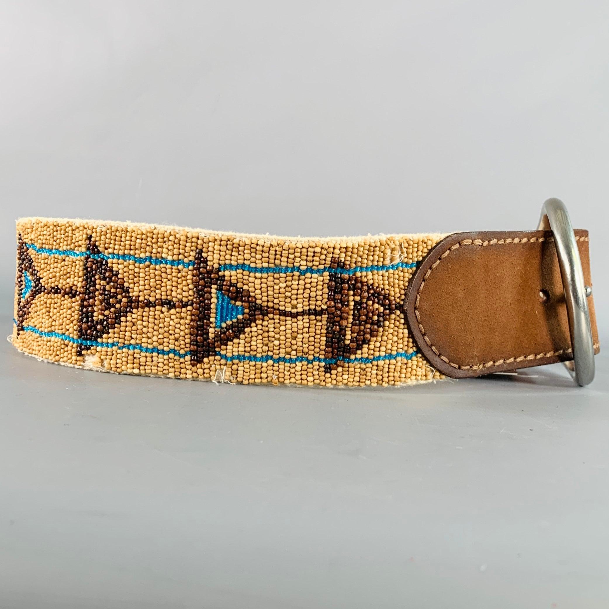 RALPH LAUREN belt in a beige, turquoise, and brown beaded fabric with brown leather trim featuring a geometric beaded design, wide style, and a large silver tone metal buckle. Good Pre-Owned Condition. Signs of wear on beading, as is. 

Marked:  