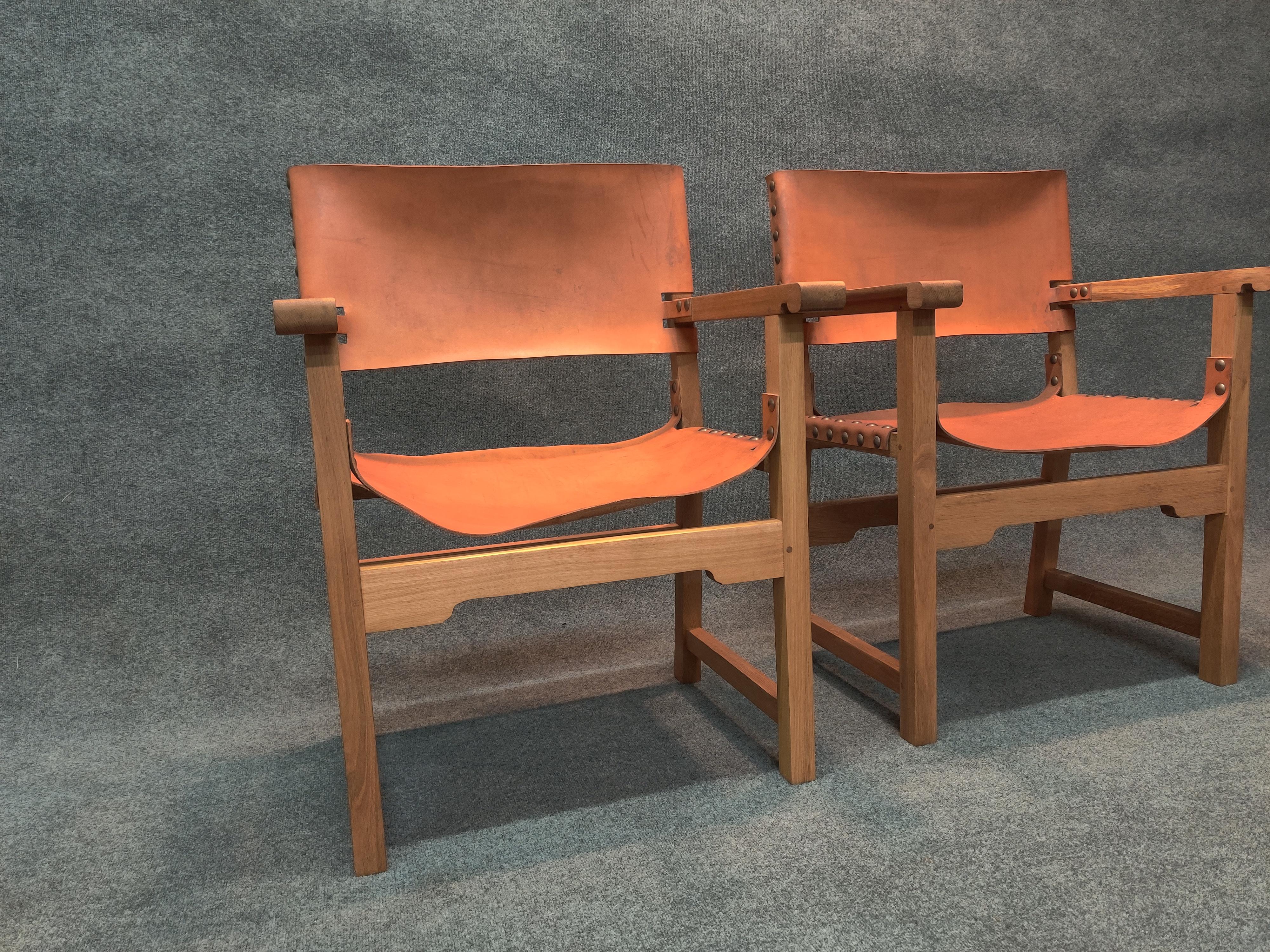 Pair of handsome and well-made director style armchairs. High quality construction and materials are evident. Frames are constructed of white oak in a natural finish. Seats and backs are of saddle leather and are secured with large brass studs. Some