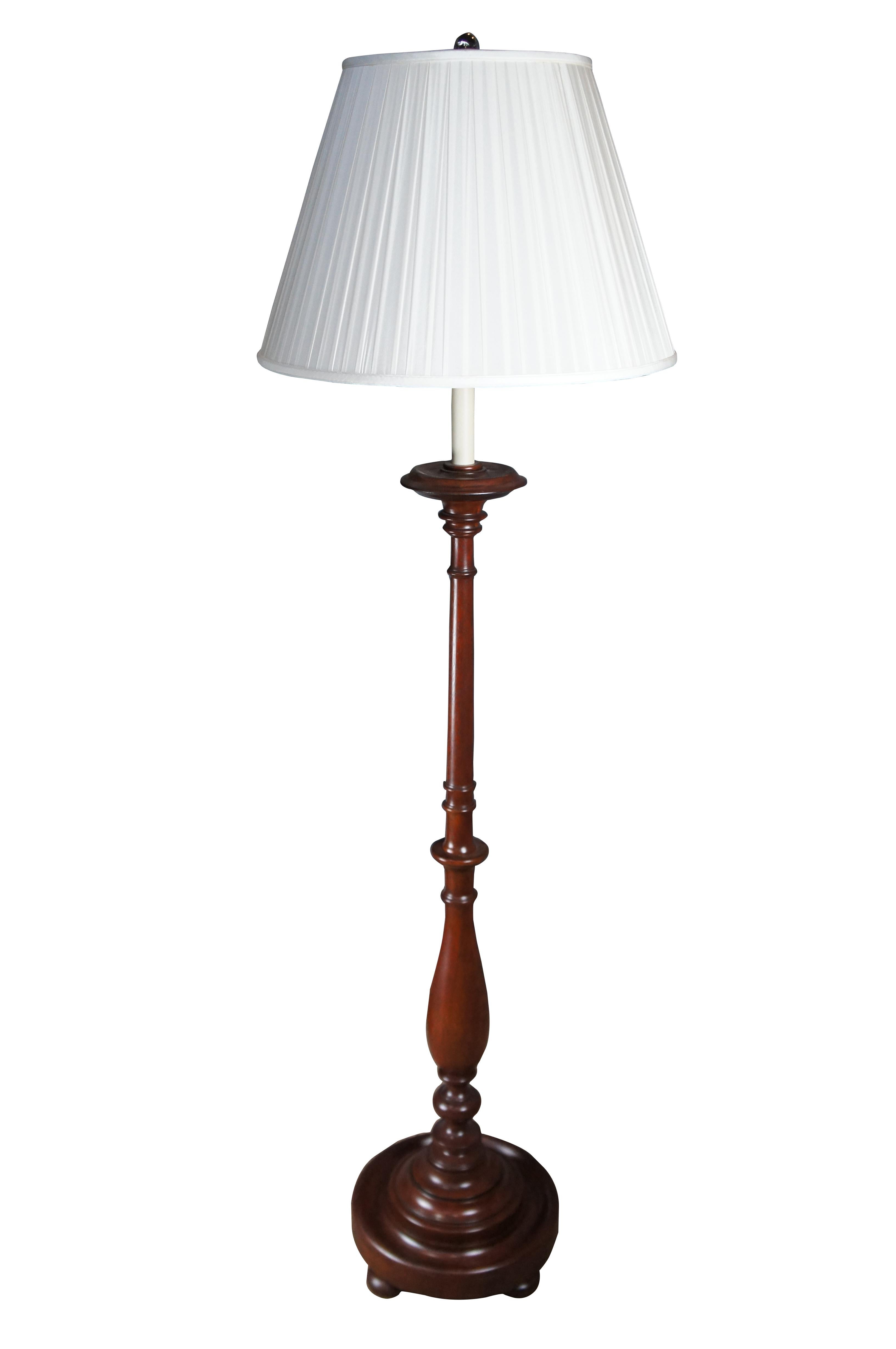 A traditional rich brown mahogany floor lamp by Ralph Lauren. The lamp is in the form of a large Early American / Colonial candle stand with candlestick center and adjustable harp allowing the shade to be raised / lowered. Features a baluster turned