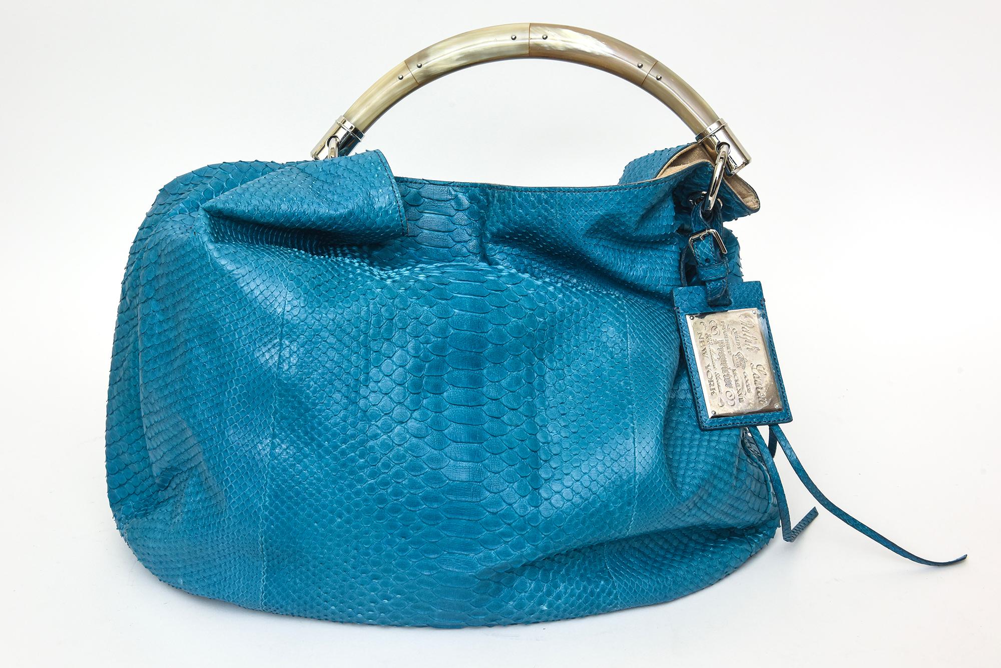 This ultra gorgeous and chic Ralph Lauren turquoise python arm and shoulder bag has a top handle made out of bone like material. The handle is embellished with small silver studs and silver hardware. There is a silver attached plague or tag of Ralph
