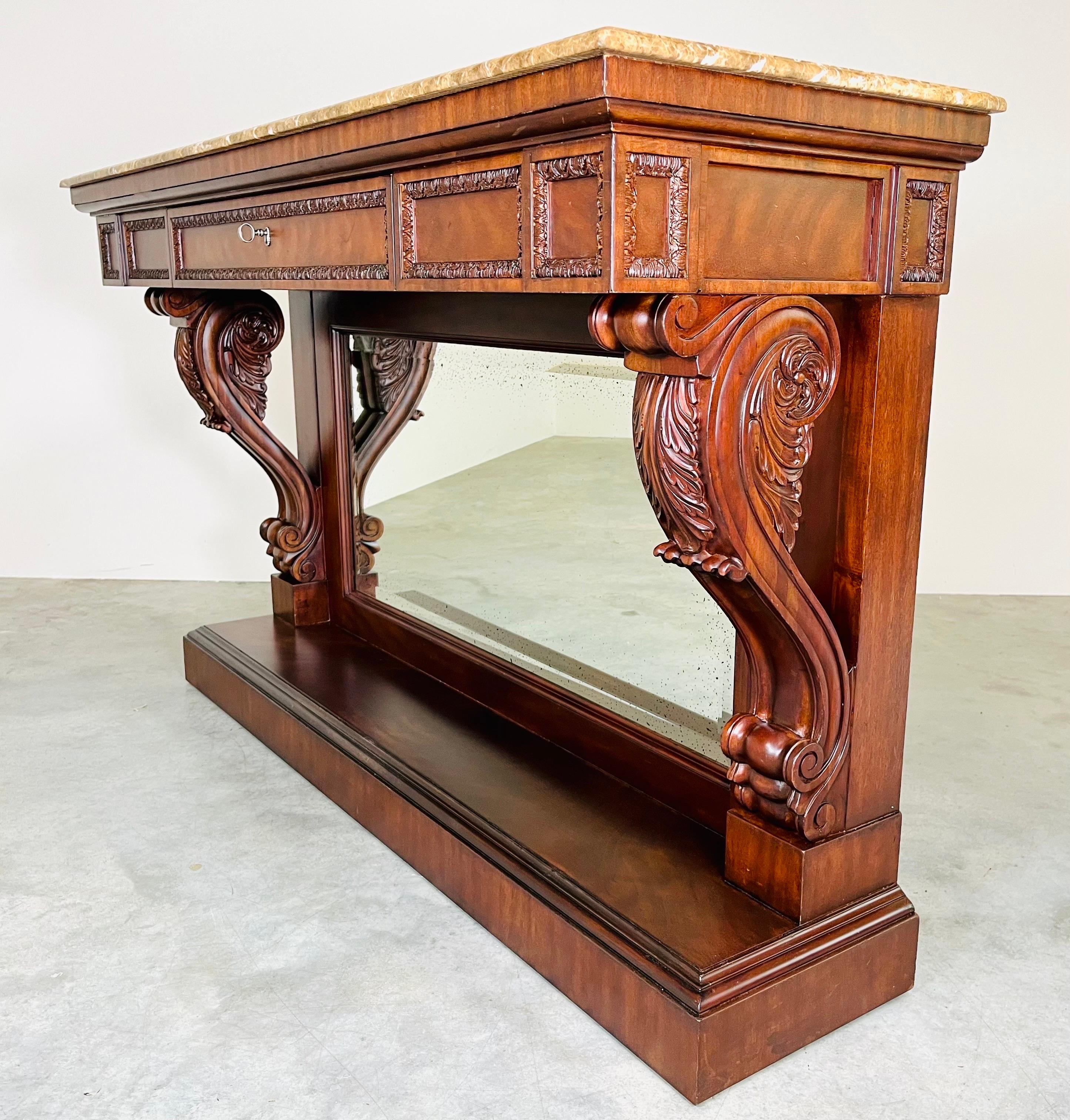 A stunning console or hallway table having Italian marble top, antiqued mirror center and carved mahogany throughout by Ralph Lauren Fine Furniture. Console features a locking center drawer with heavy steel key and durable lock. Stunning details