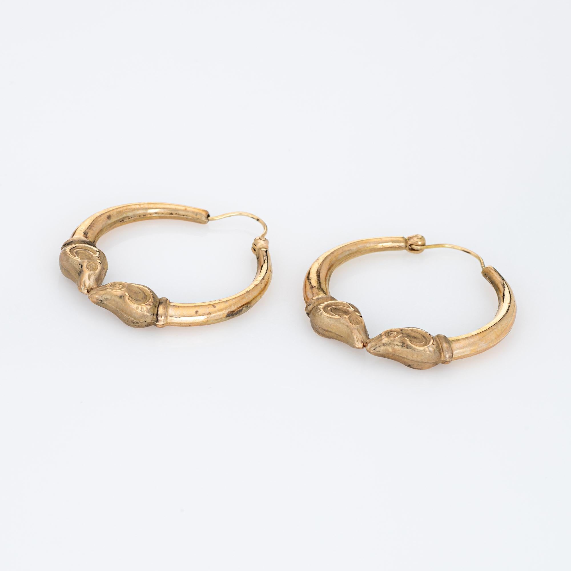 Fine detailed pair of Ram head hoop earrings crafted in 14k yellow gold. 

The stylish earrings feature two satin finished ram's heads to the base of the hoops. The earrings are fitted with wire backings for pierced ears.

The earrings are in very
