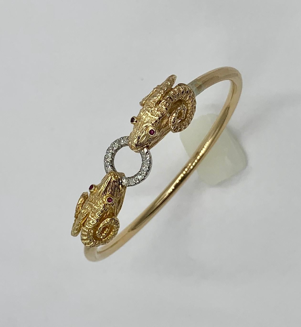 The stunning bangle bracelet is set with two Ram, Sheep, Aries heads.  The mouths of the Rams hold a Diamond circle and the eyes of the Rams are fine red Rubies.  The bracelet is a classic Greek Revival motif.  It is exquisite with beautiful three