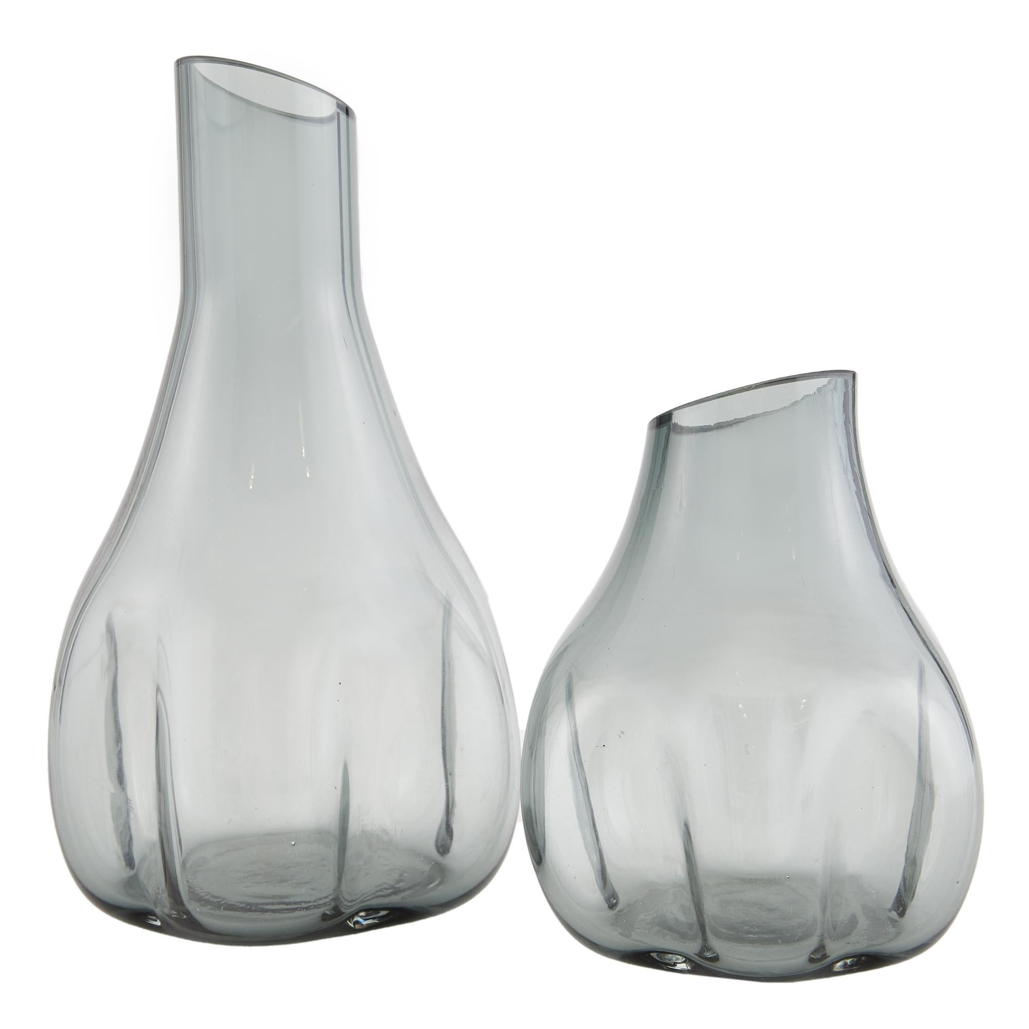 Rampart Vasen, 2er Set - Die skulpturalen und fließenden Formen der Rampart Vasen bringen Bewegung und moderne Kunst in jede Einrichtung. Jede Vase ist aus blauem Rauchglas gefertigt und zu einer von der Schmelze inspirierten Silhouette geformt, die