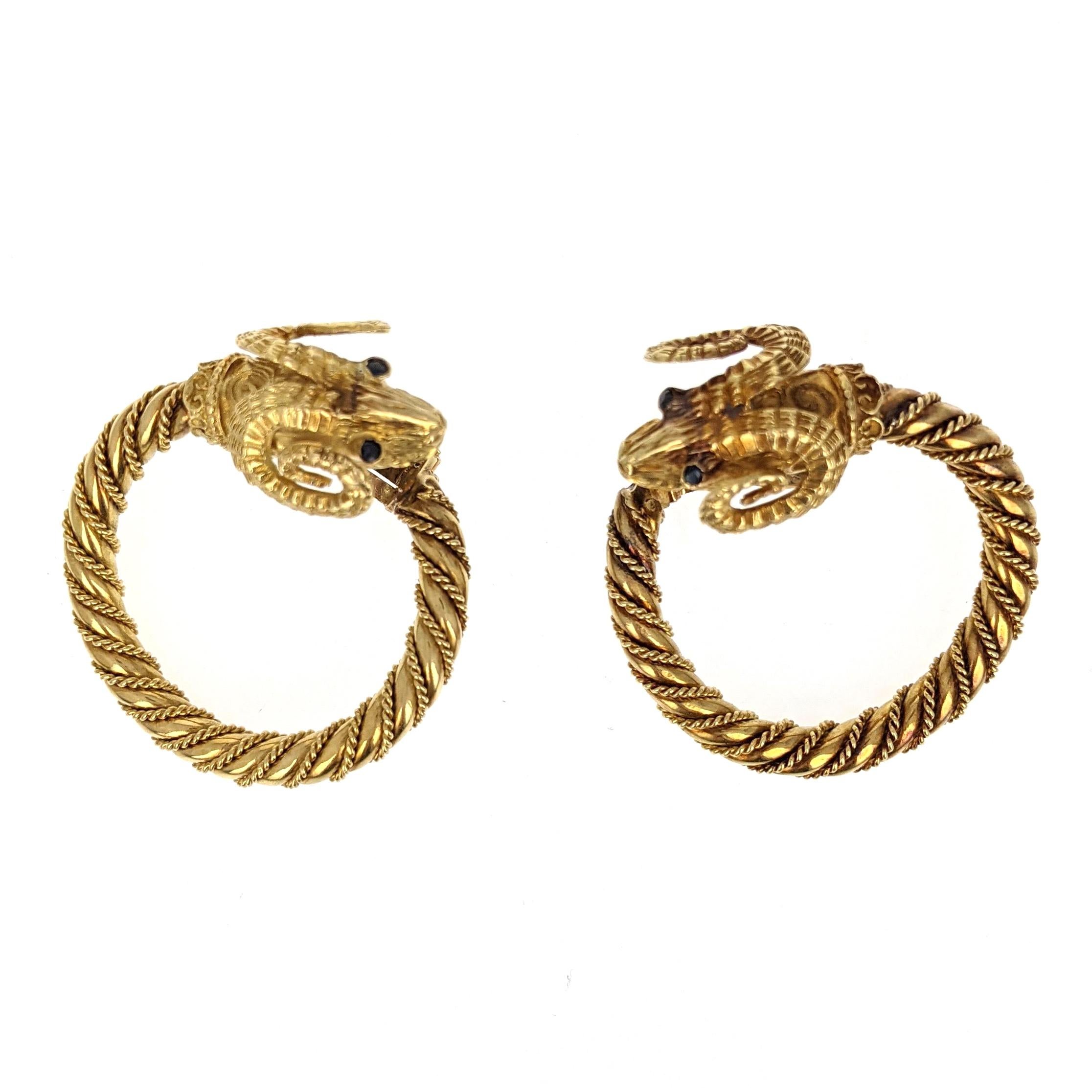 Each designed as a hoop with twisted metal spiraling around and topped with a ram's head. Mounted in 18 karat yellow gold. 