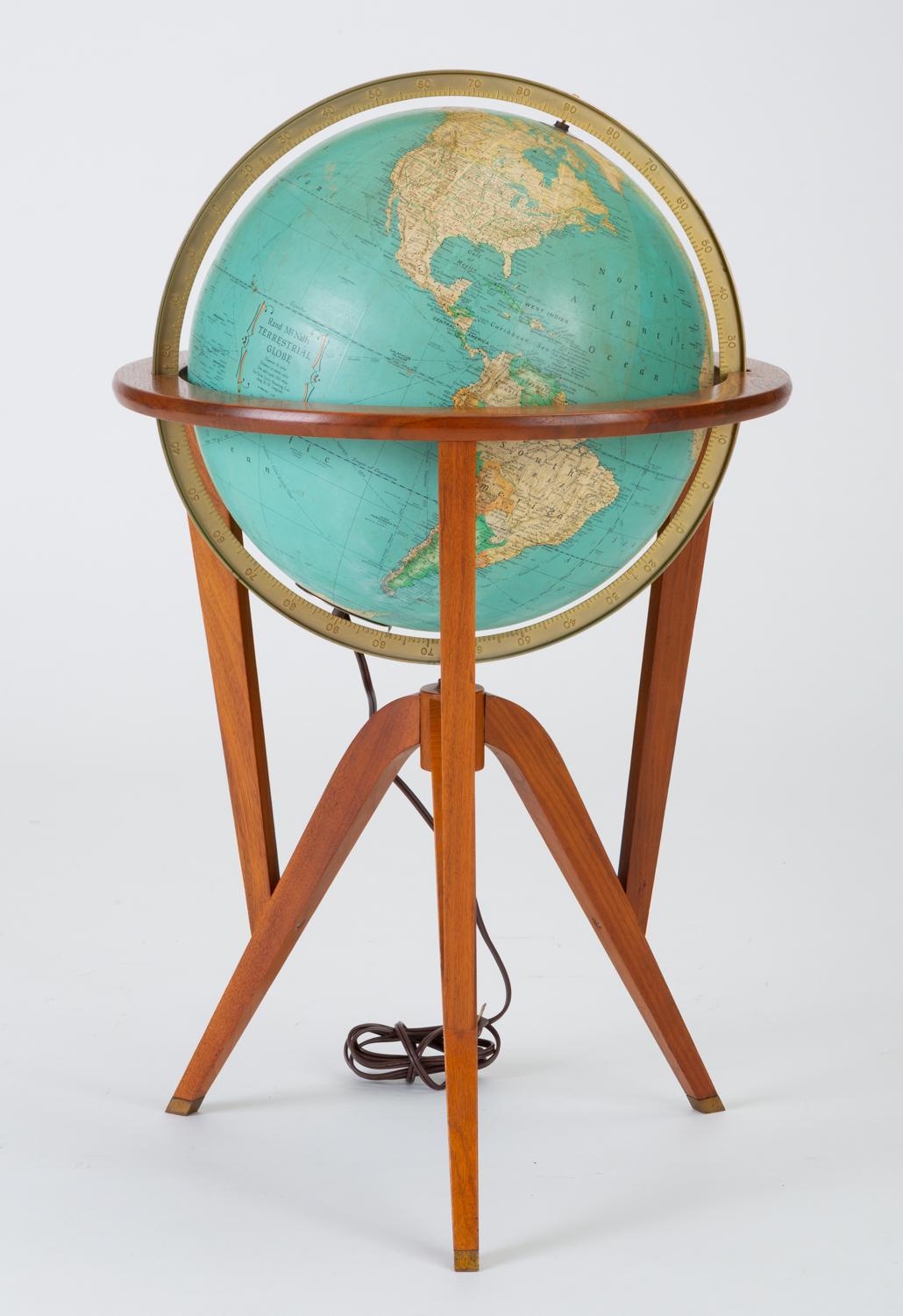 An illuminating globe in a walnut stand designed by Edward Wormley (of Dunbar) for map company Rand McNally. Dubbed the “Cosmopolitan,” the globe has an X-base of four tapered walnut legs with brass feet, and a broad ring of walnut to support the
