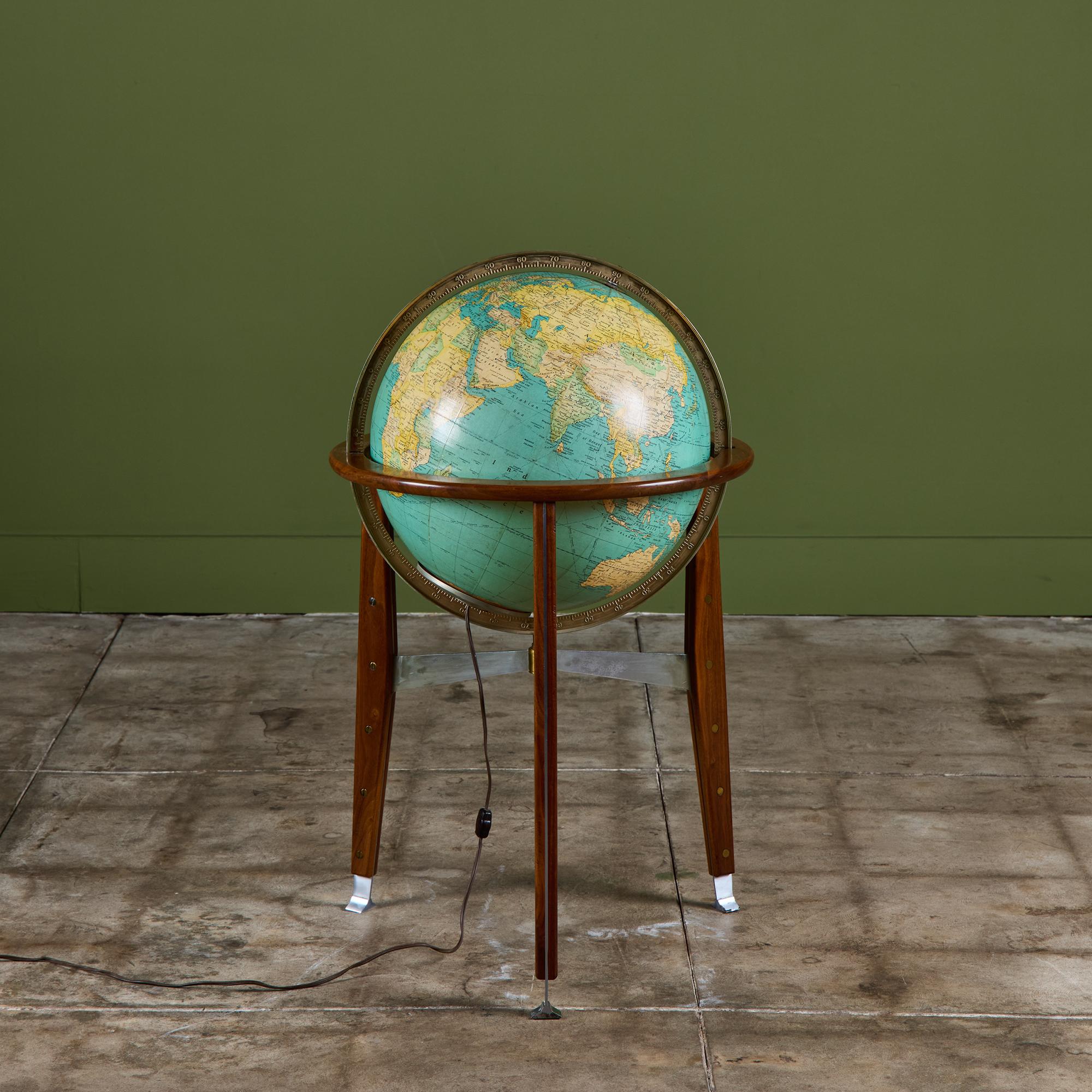 Illuminating globe in a walnut stand designed by Edward Wormley for map company Rand McNally. The globe features three walnut legs with stainless steel sandwiched between each leg and fastened stud detail down each leg with stainless steel feet. The