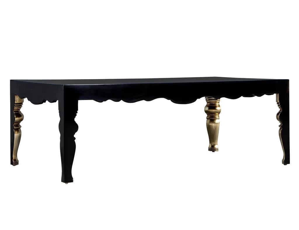 Randall Tysinger mons cocktail table in black. It is finished in a high gloss black lacquer with clean exterior lines while the underside and interior of the table is ornately carved in a traditional fashion with a beautiful gold leaf feature with