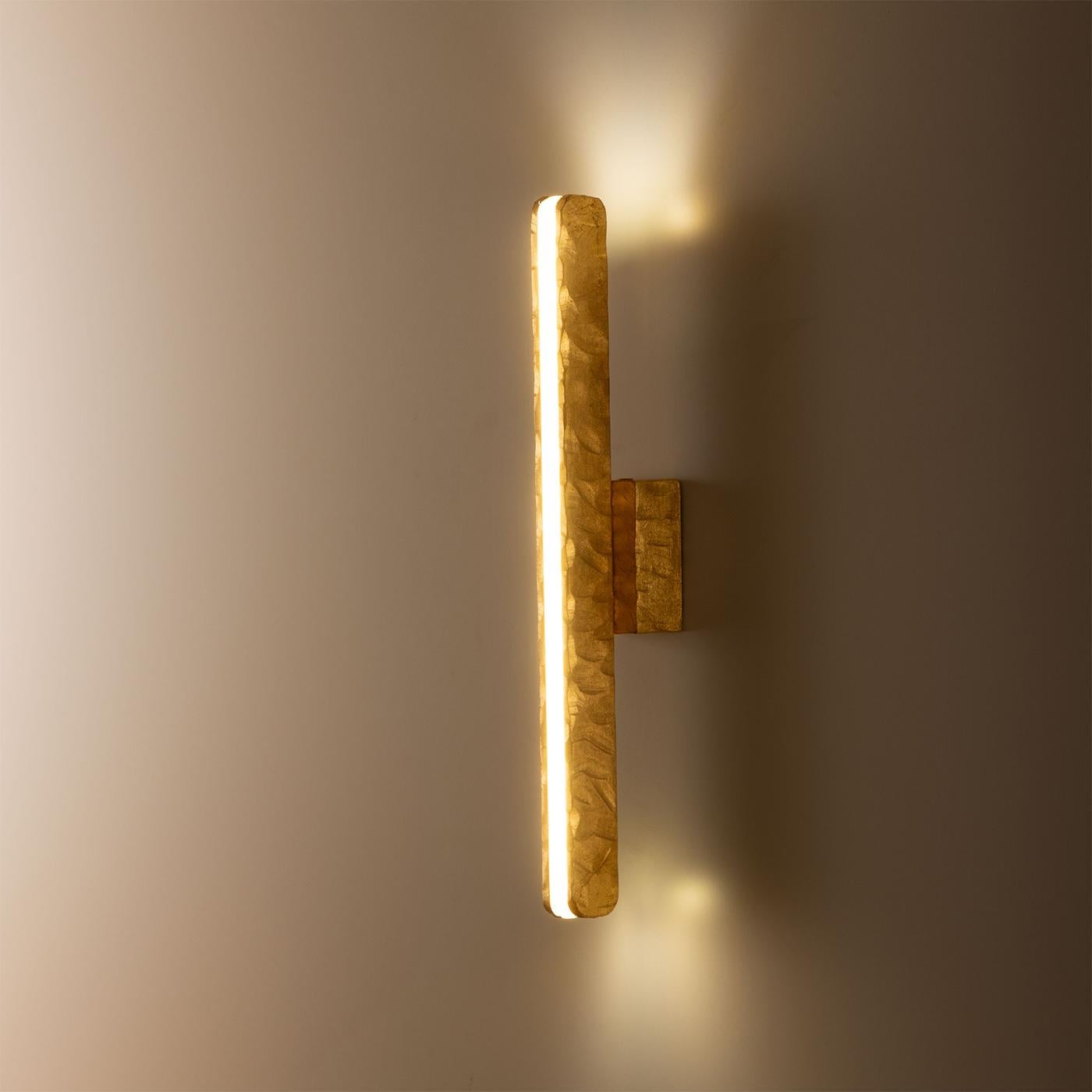 Esta lámpara de pared, una celebración de la elegancia atemporal, desprende refinamiento por su silueta elegante y vertical. Distinguida por su forma esbelta y alargada, proyecta una elegante iluminación frontal que realza cualquier espacio interior