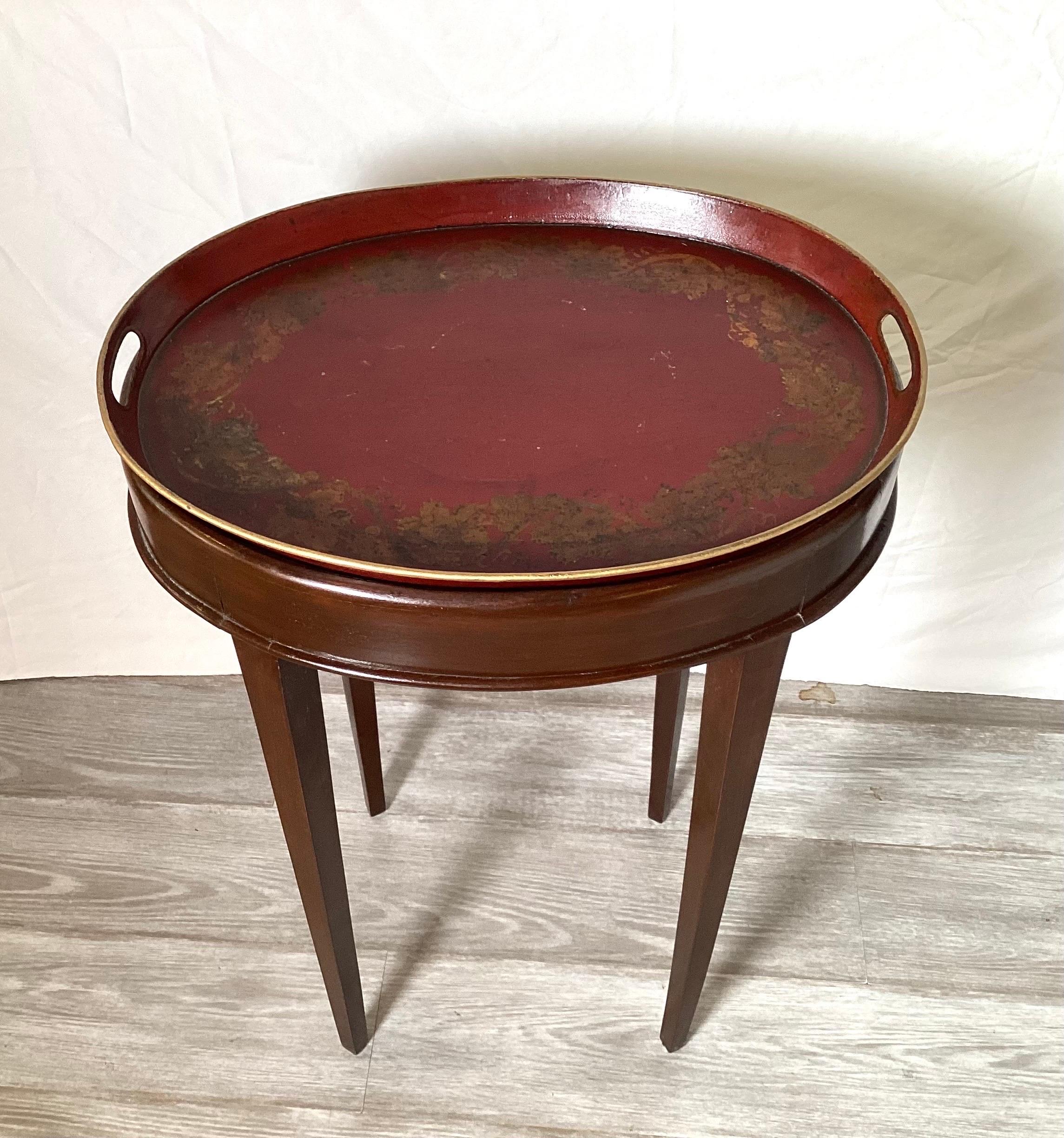 An Antique 19th century Italian Tole tray with custom mahogany base. The oval tray in a cinnabar red color with light gold details. The base, made in the 1920s of solid Mahogany 20 wide, 15 deep, 27.5 high.