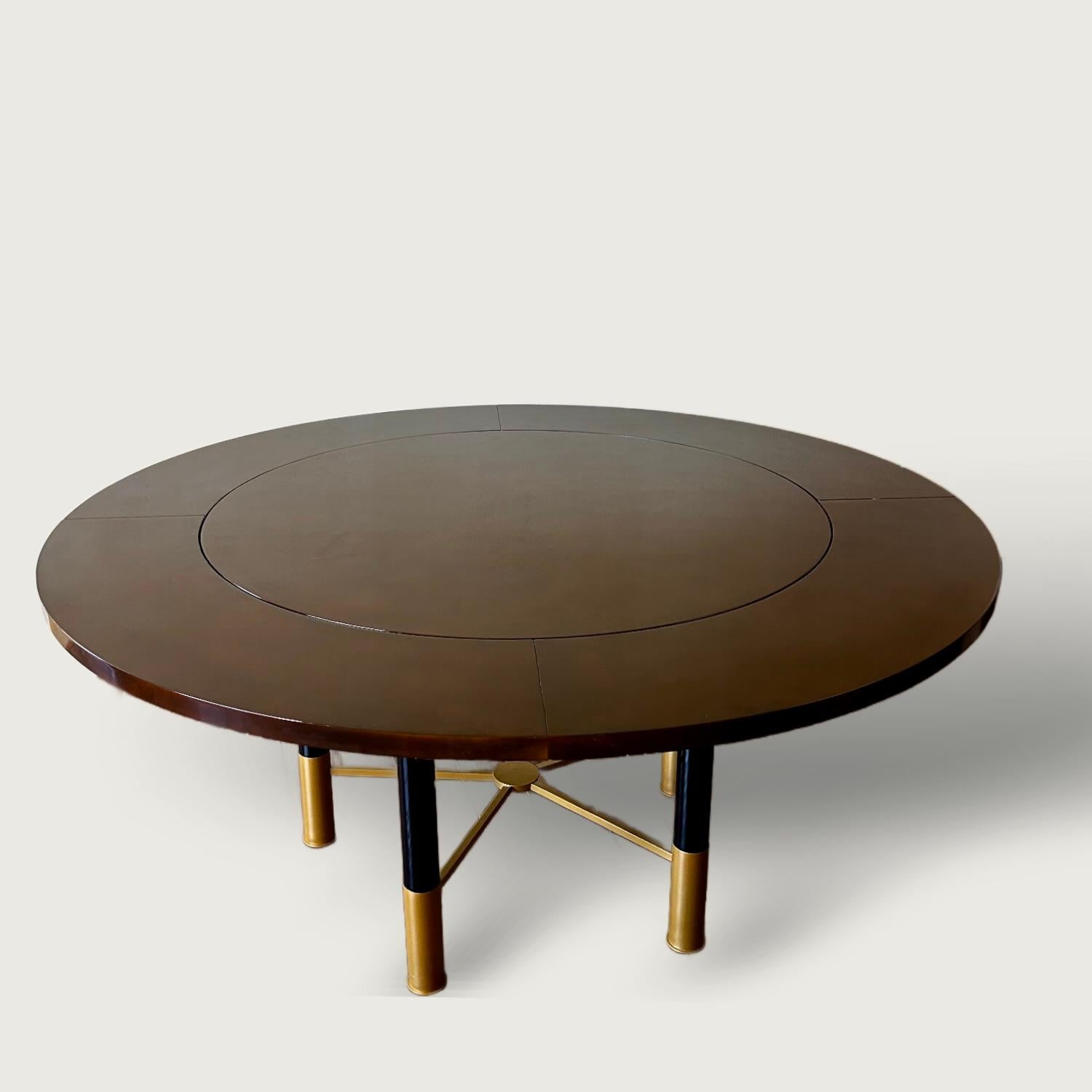 A rare and exceptional Raphaël extendable dining table finished in his signature Béka lacquer, the technique produces a subtle two tone burnt umber appearance, with five black lacquered metal legs and gilt bronze feet and spacers. 

Literature: A