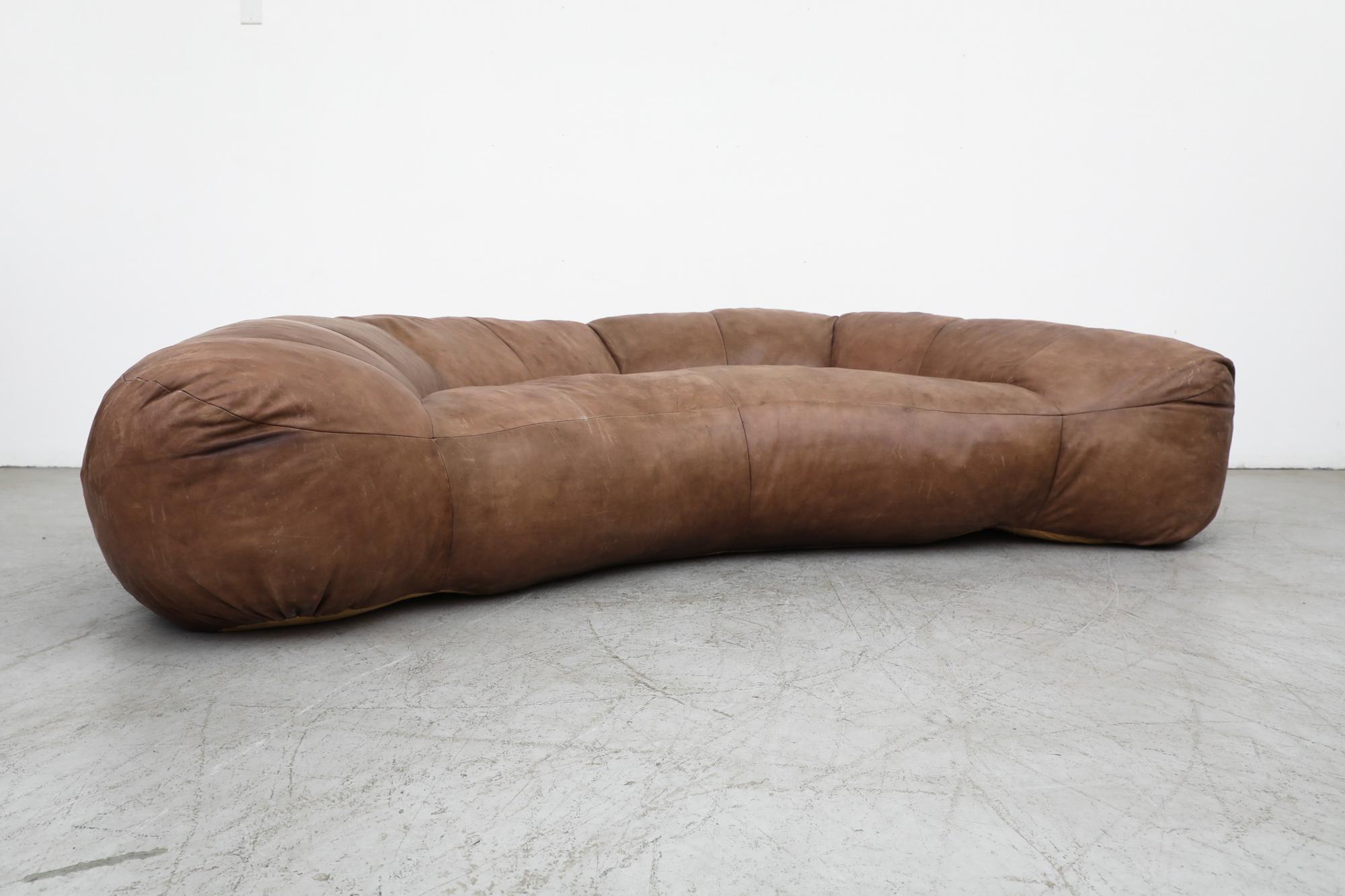 A Raphael Raffel designed, 1970s, made-to-order natural leather Croissant Sofa for Honore Paris. Raphael Raffel (1912-2000), who trained at the École des Beaux Arts, was a well-known interior decorator whose work was collected by the likes of
