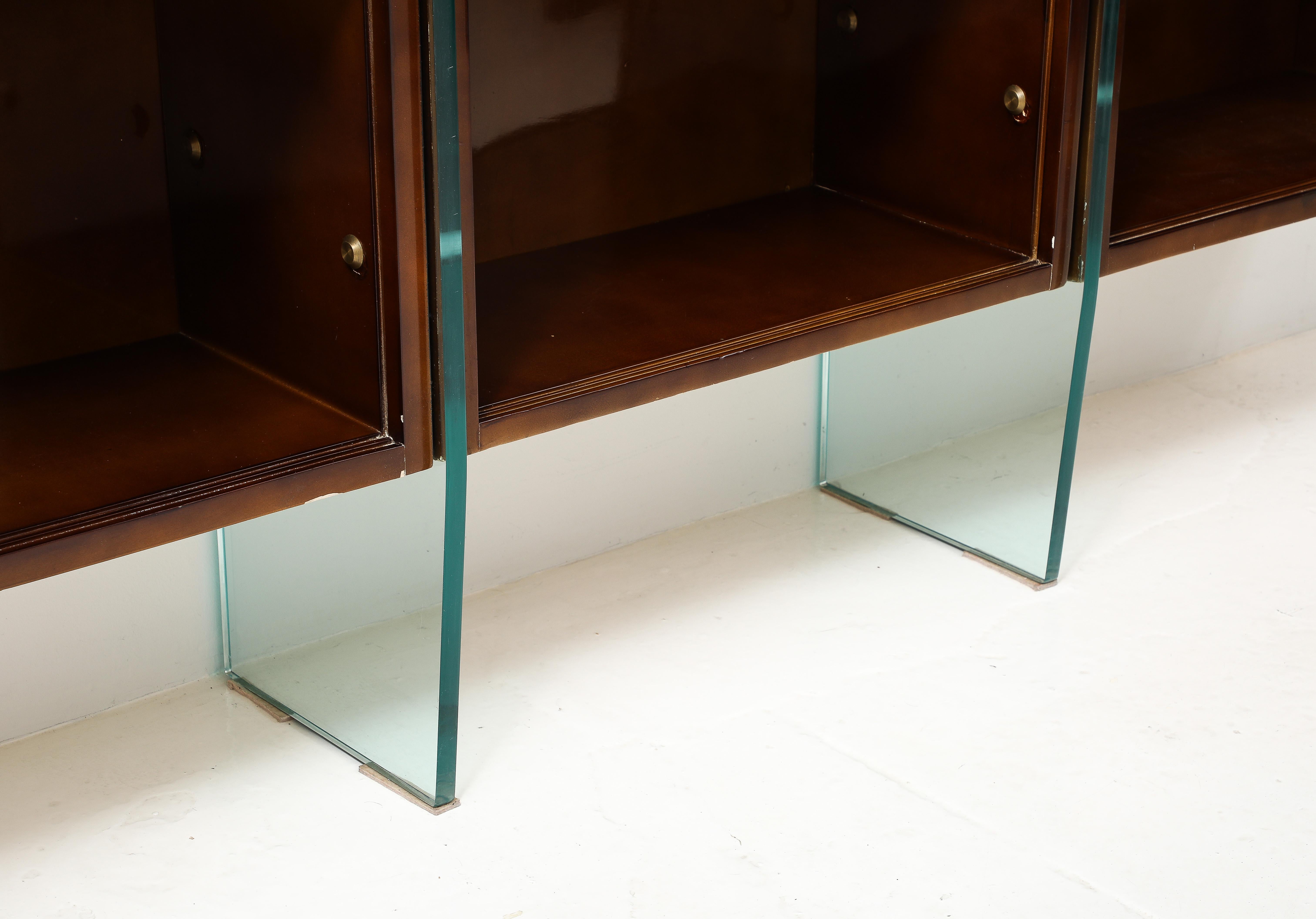 Exceptional triple floating bookcase in beka lacquer with bronze accents on saint gobain glass legs.
