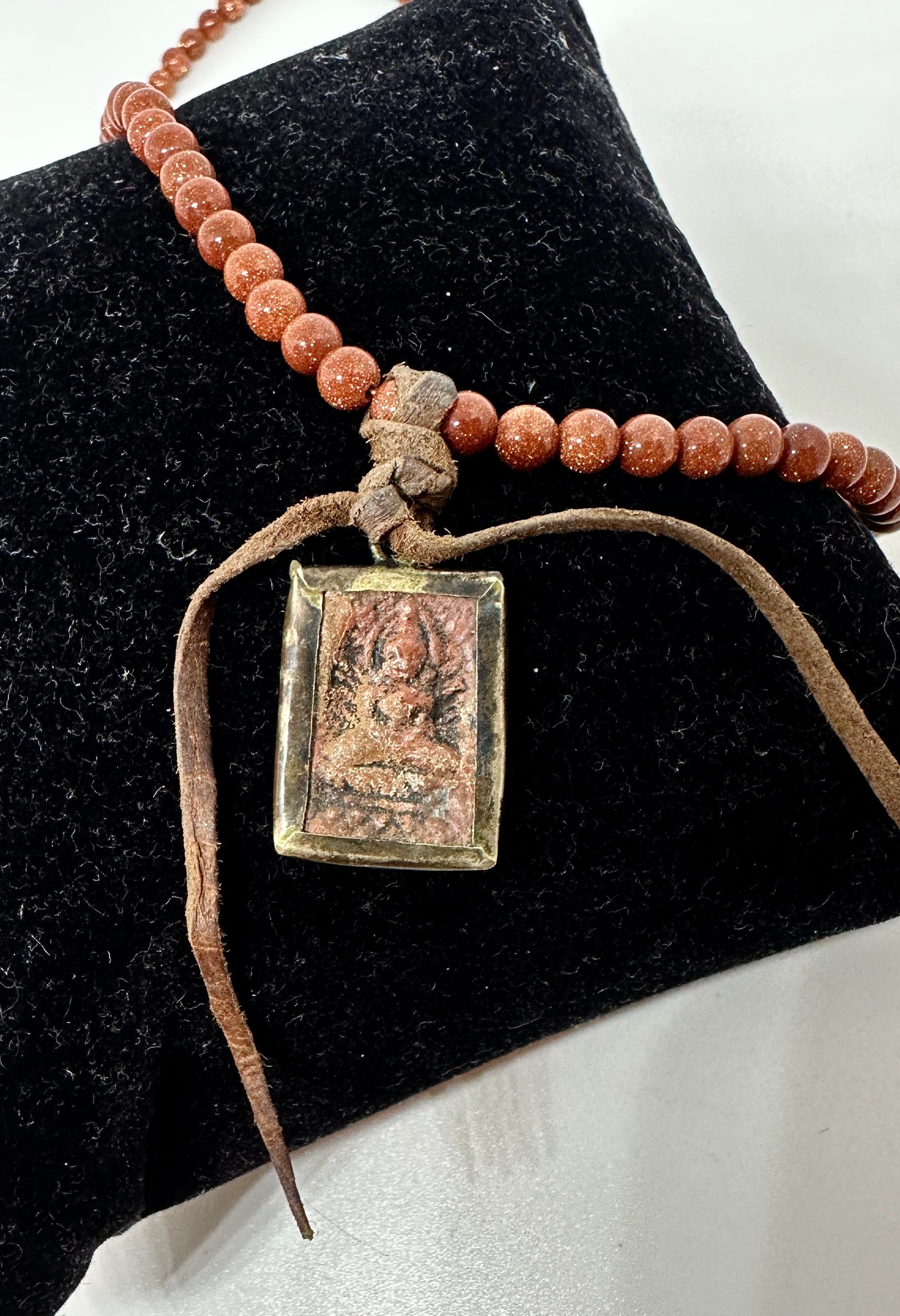 Indulge in an absolutely fantastic Buddha and Goldstone Necklace from the estate of the legendary Raquel Welch!  The magnificent jewel features an antique pendant in stone that is hand carved with a depiction of the seated Buddha.  The buddha is set