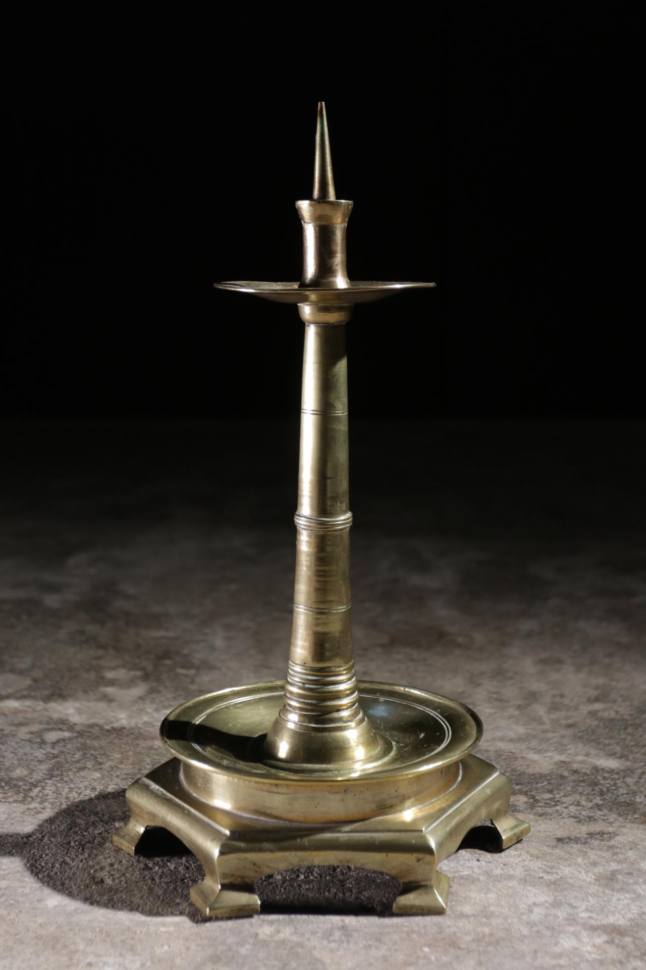A rare 16th century brass pricket candlestick with circular stem, drip pan on a two tier Stand, circular and octagonal on six feet. 

Measures: 39.5 cm high / 22 cm diameter.