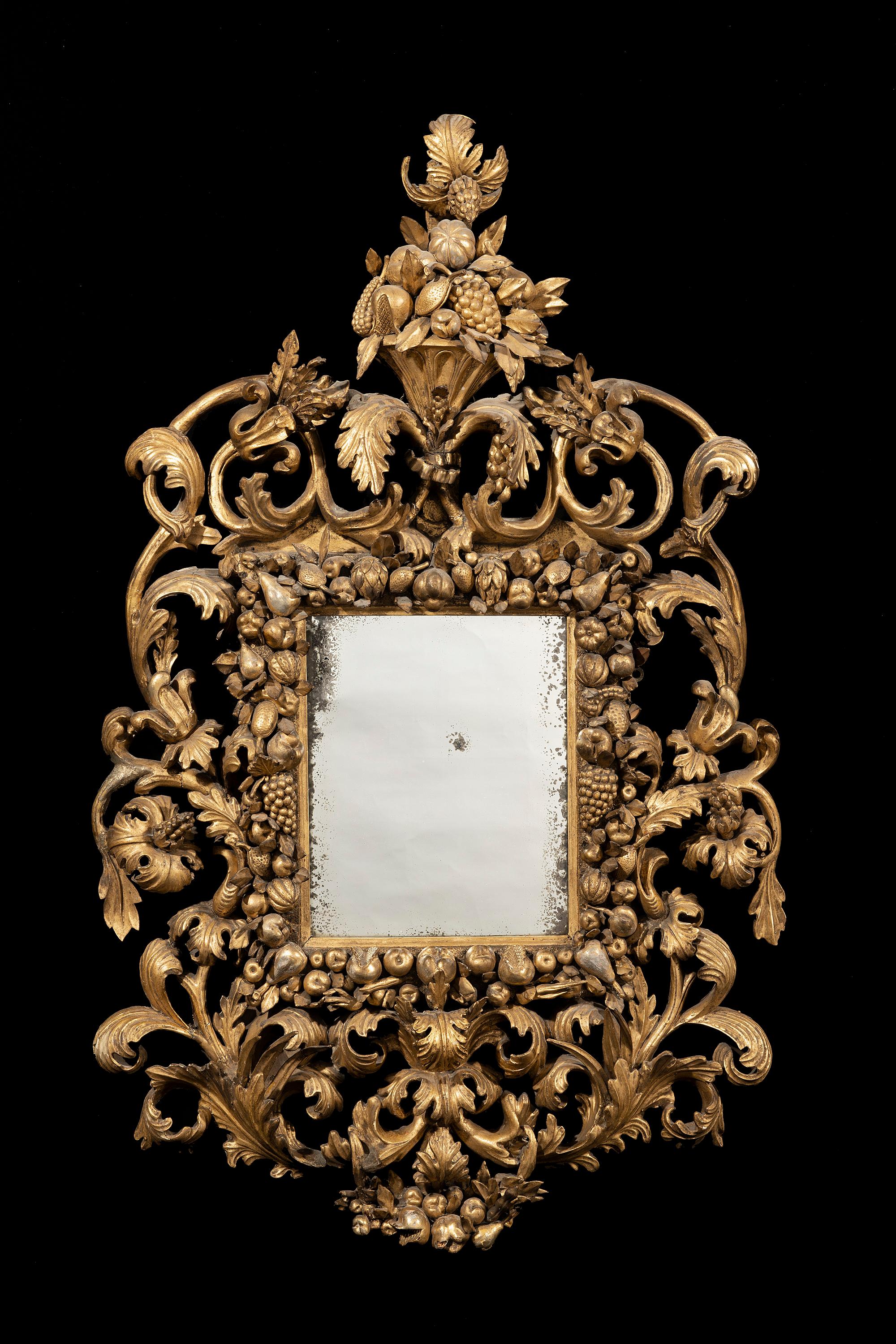 The flowers and fruit urn to the top of the mirror sit above acanthus leaf decoration surmounted on a robust rococo outer frame with scrolling acanthus leaves and large flower heads. The apron is profusely carved with scrolled acanthus leaves that