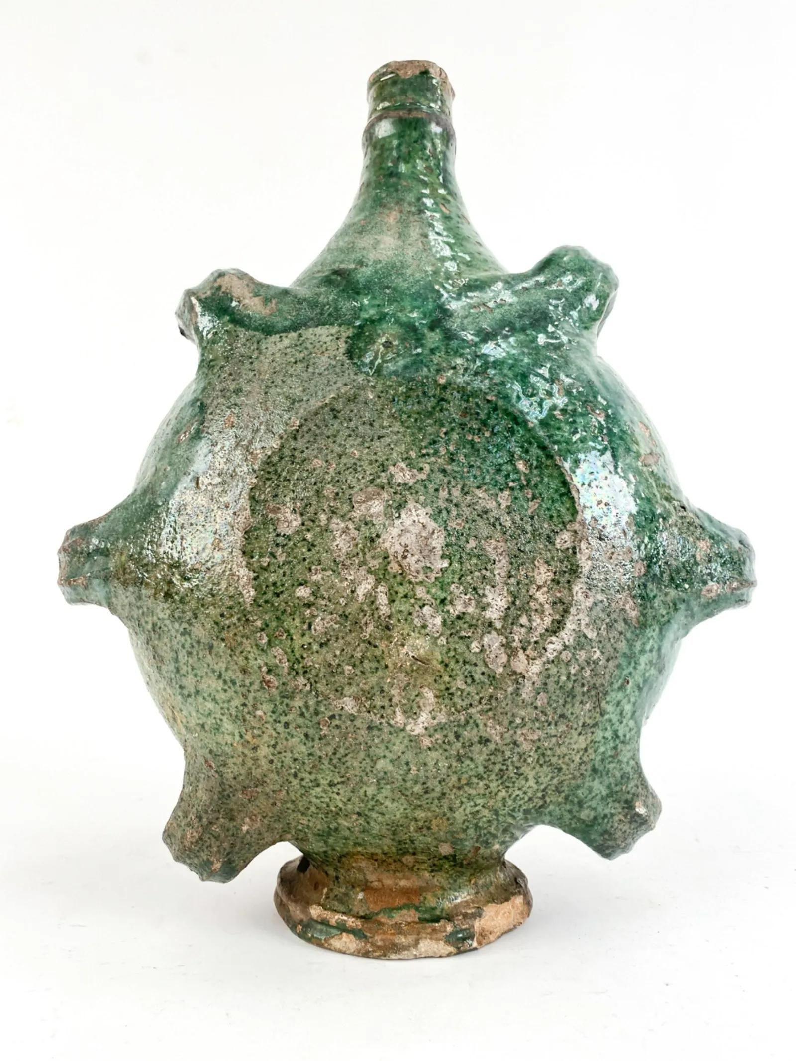 A rare French Provencale region water vessel, late 17th century, in stoneware with green glaze. The vessel was designed to be held on a rope threaded through the gaps at the sides and bottom and carried like a water sac.