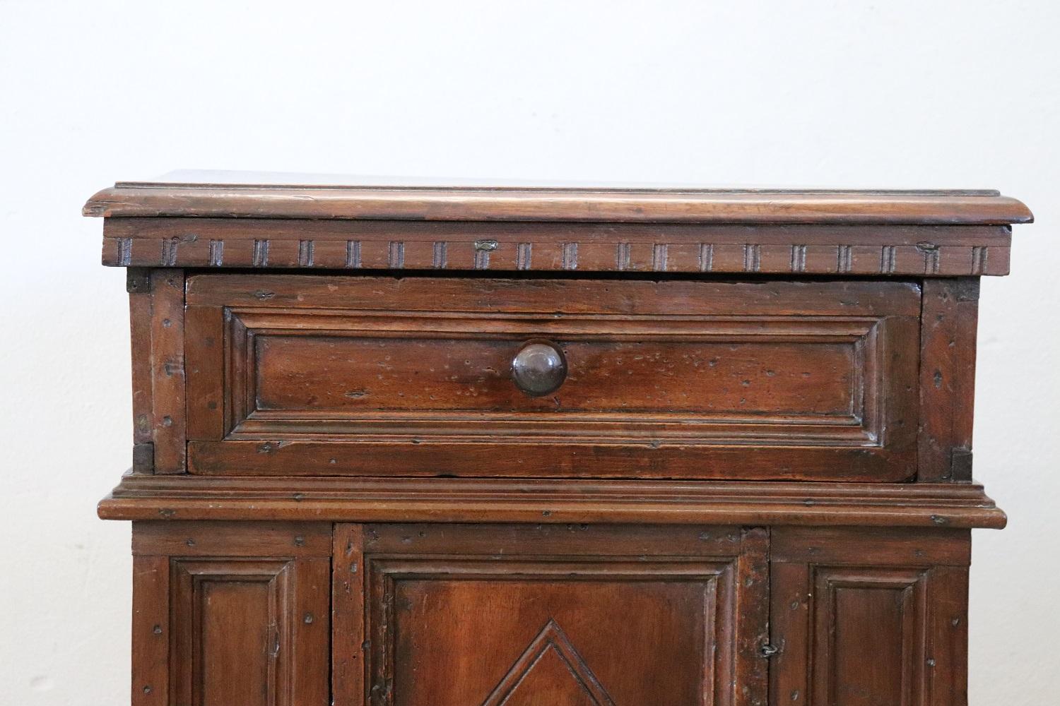 Rare and fine quality Italian Tuscany 1680s antique nightstand in carved solid walnut. On the front one comfortable drawer. Geometric decorations on the door panels and sides. Original back and nails. In antique good conditions.