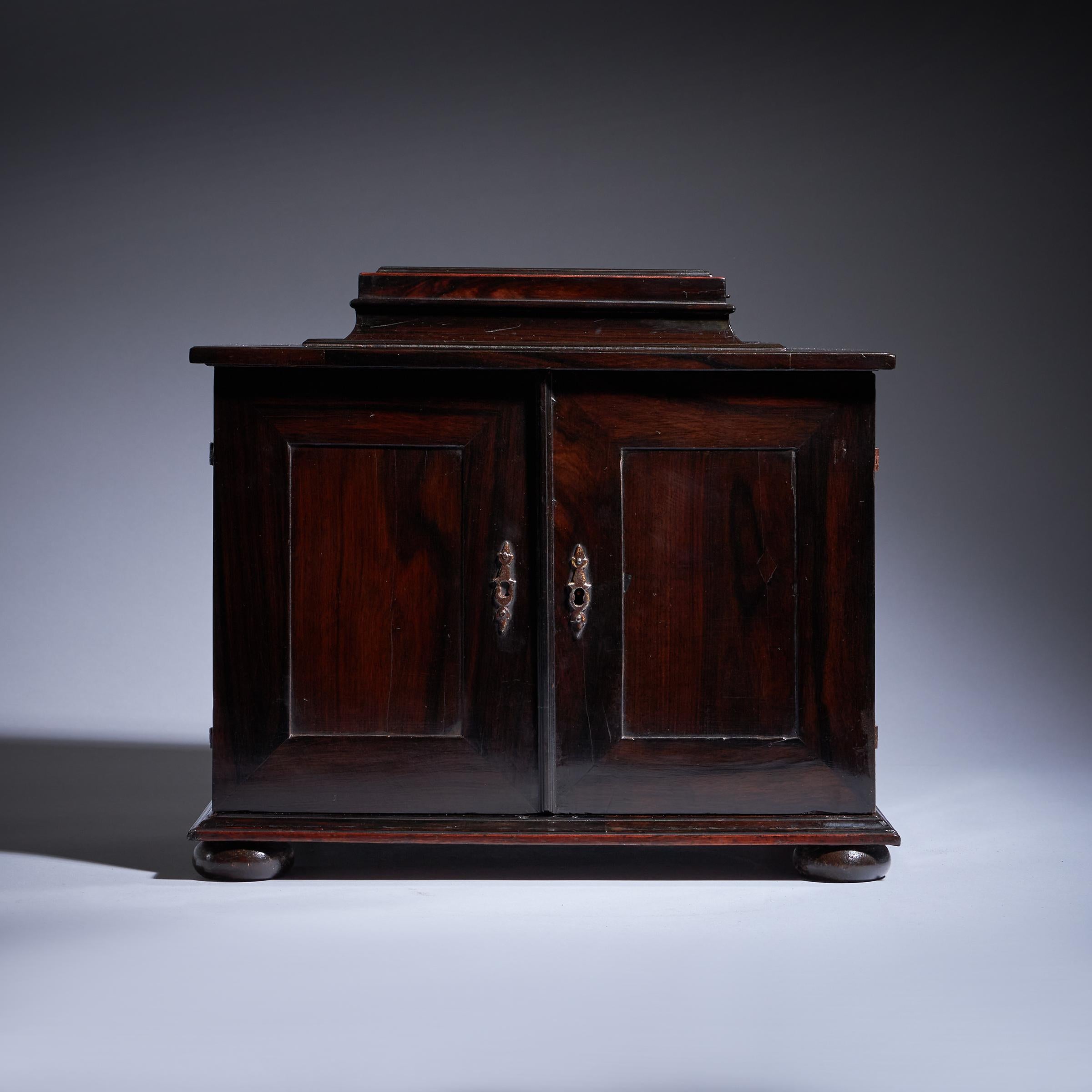 A fine and rare mid-17th century ebony veneered architectural table cabinet of diminutive proportions, circa 1640. Augsuerg. 

The moulded ebony veneered cabinet is surmounted with a gable concealing a hidden compartment accessed via a neat sprung