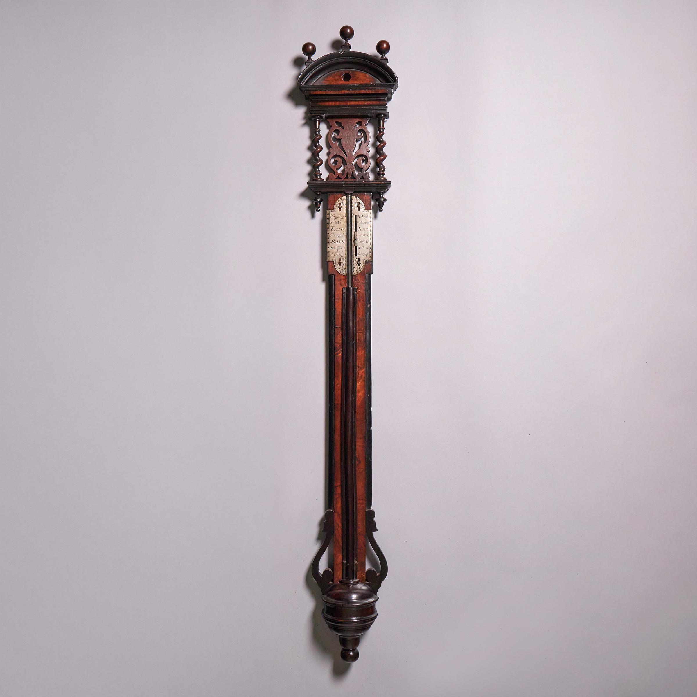 A fine and rare Queen Anne walnut barometer, unsigned, but exhibiting all the stylistic characteristics of the first quarter of the 18th century, circa 1705-1710. Made in the manner of John Patrick, the barometer features elaborately engraved